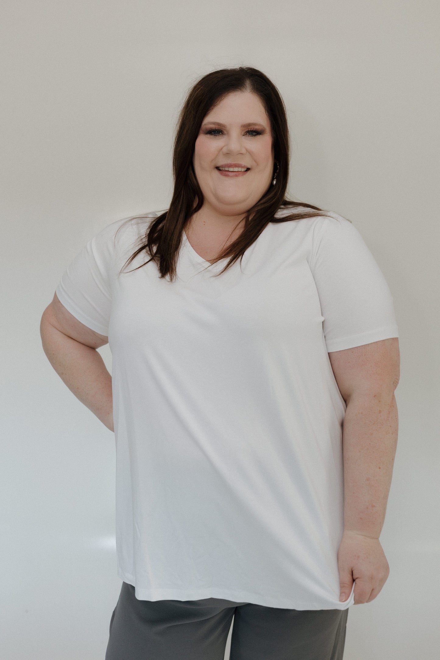 Person wearing a white t-shirt and gray pants against a plain background