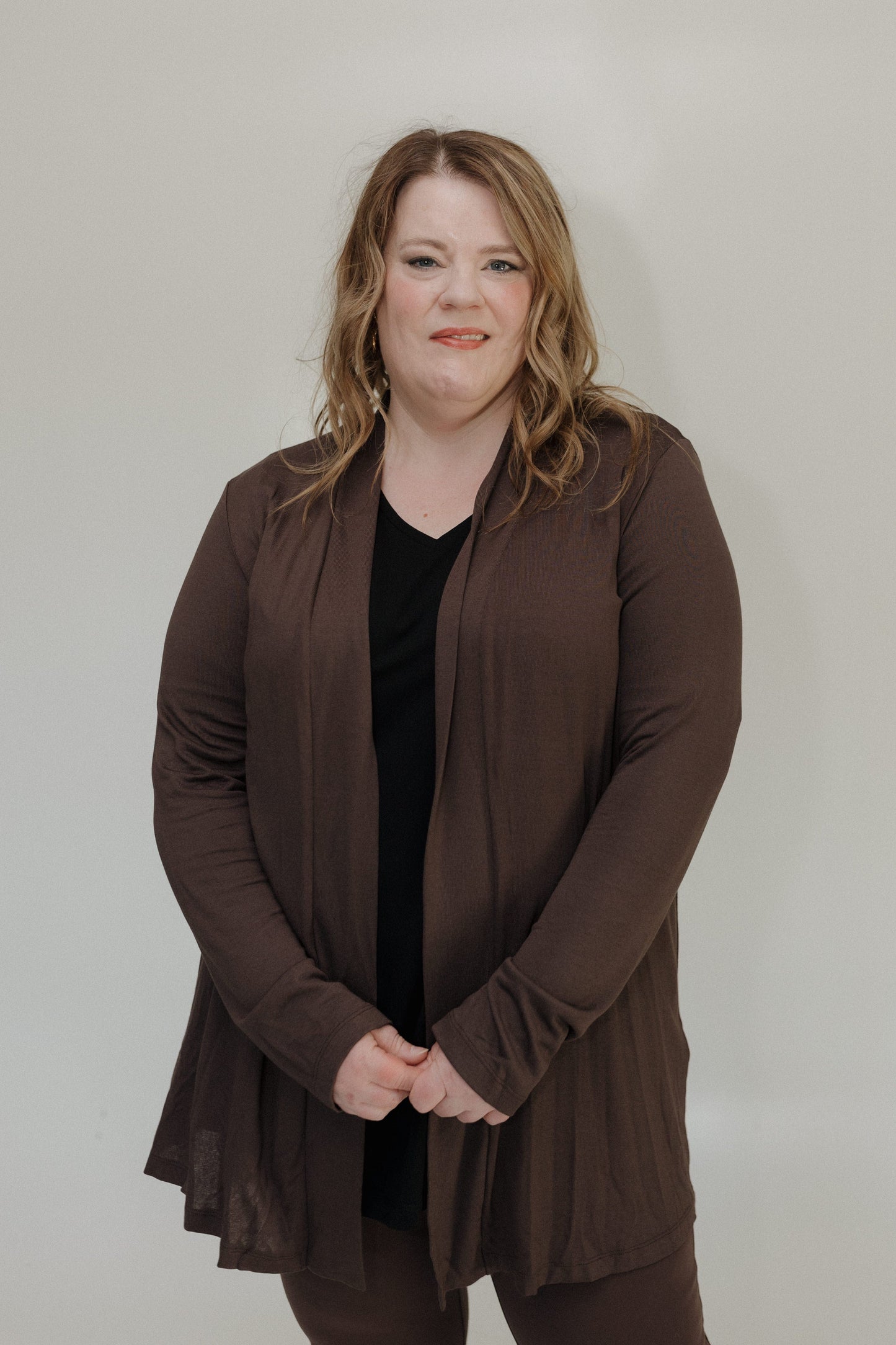 Woman wearing a brown jacket against a plain background