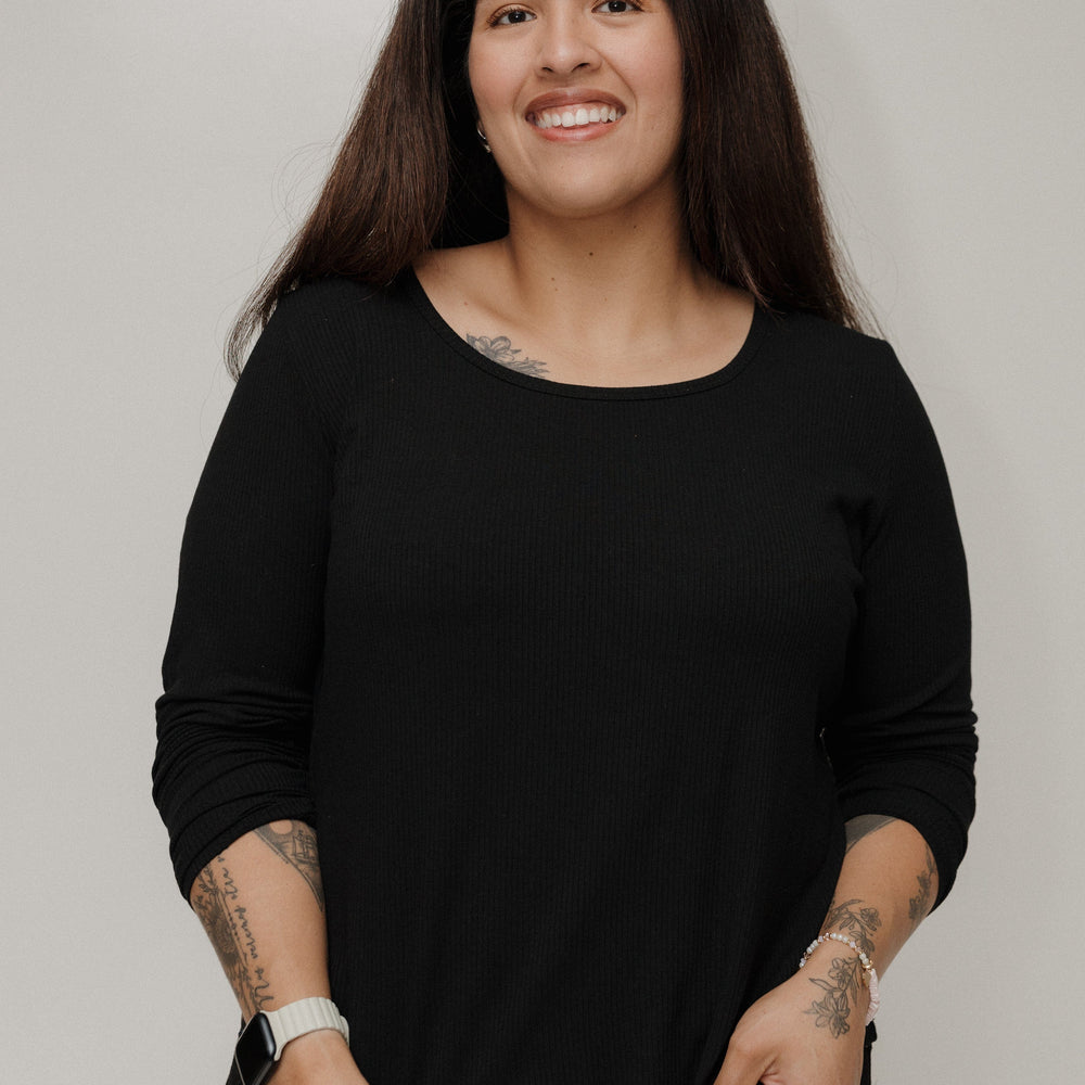 Woman wearing a black long-sleeve top against a plain background