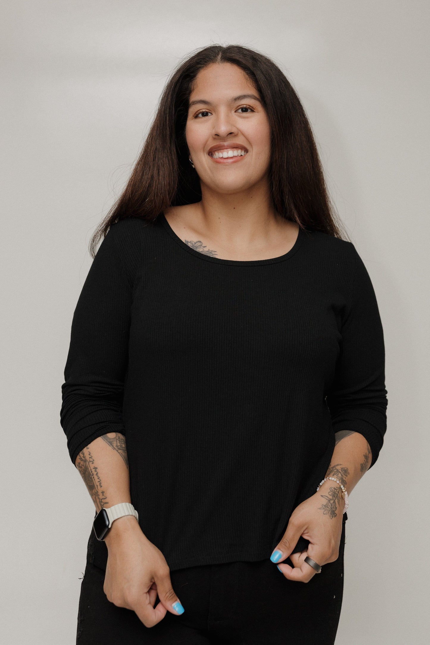 Woman wearing a black long-sleeve top against a plain background