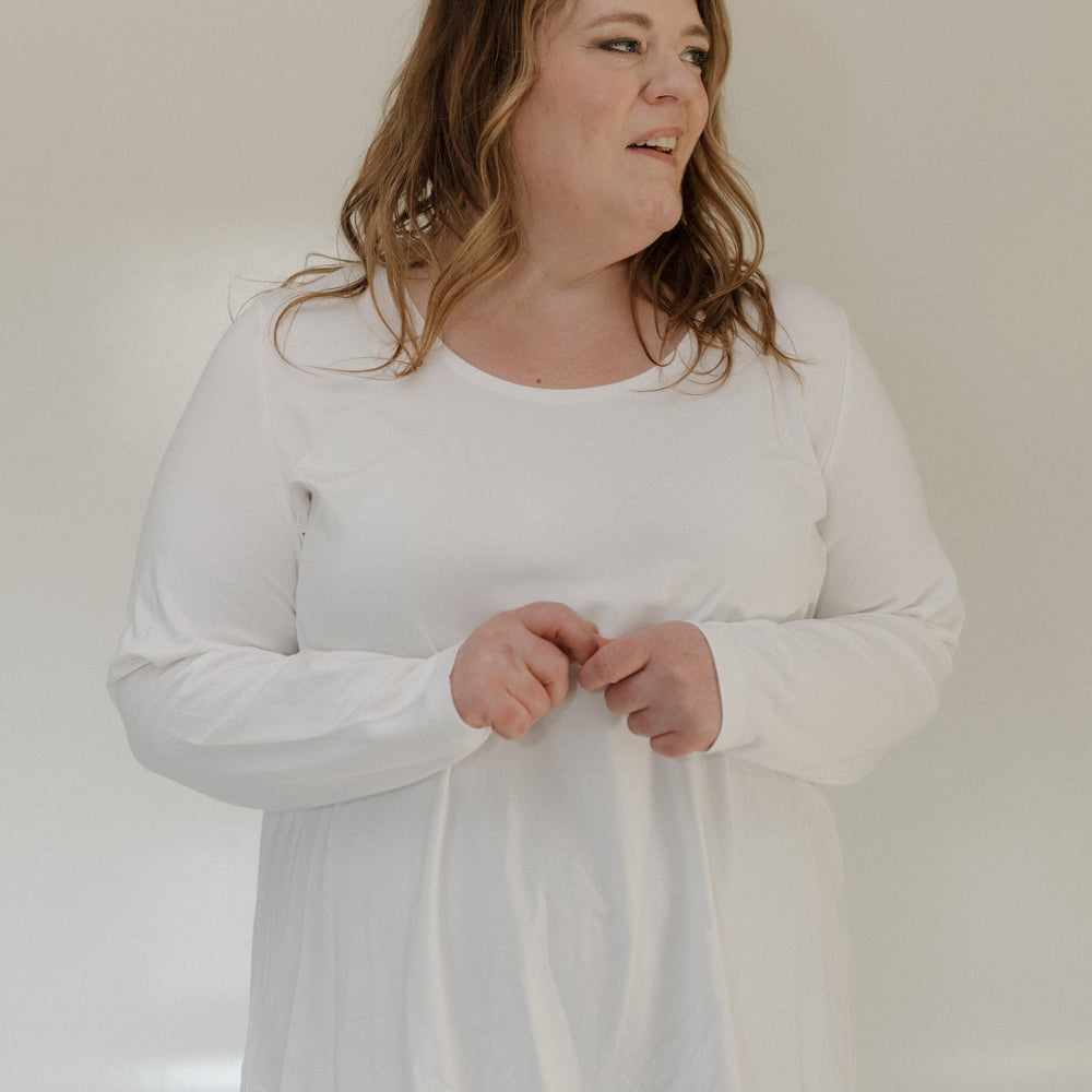 Woman wearing a white long-sleeve shirt against a plain background