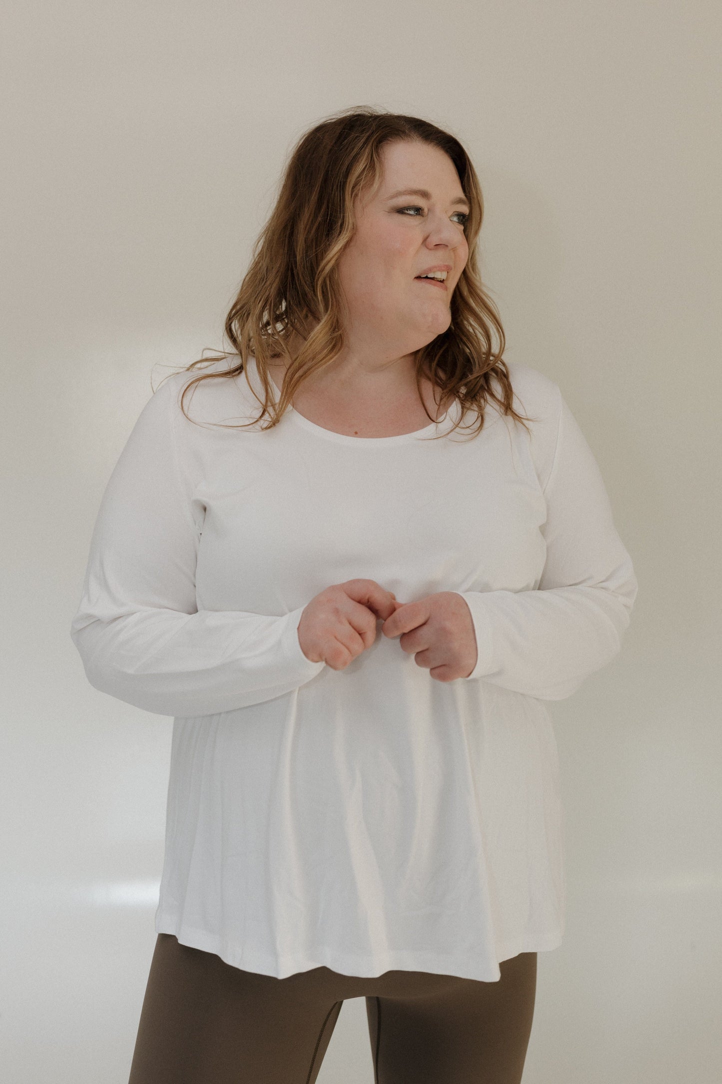Woman wearing a white long-sleeve shirt against a plain background