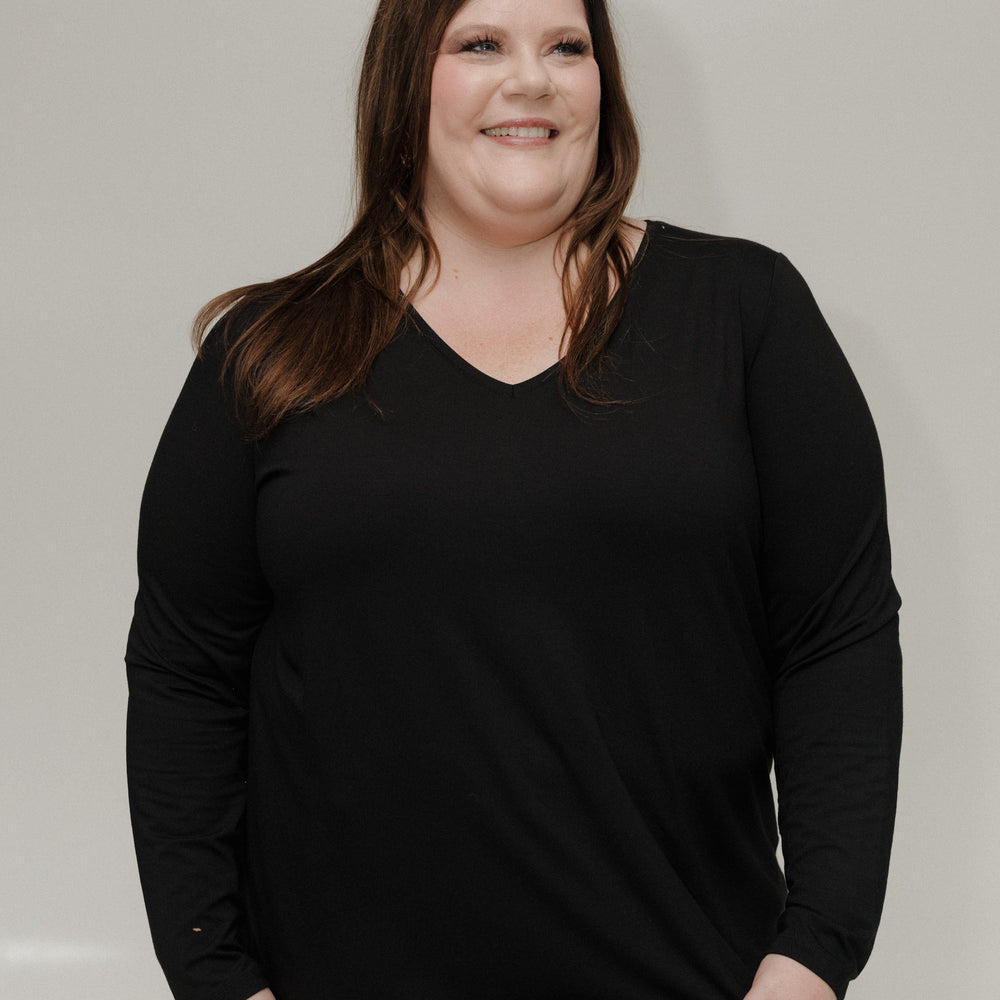 Woman wearing a black long-sleeve shirt against a plain background