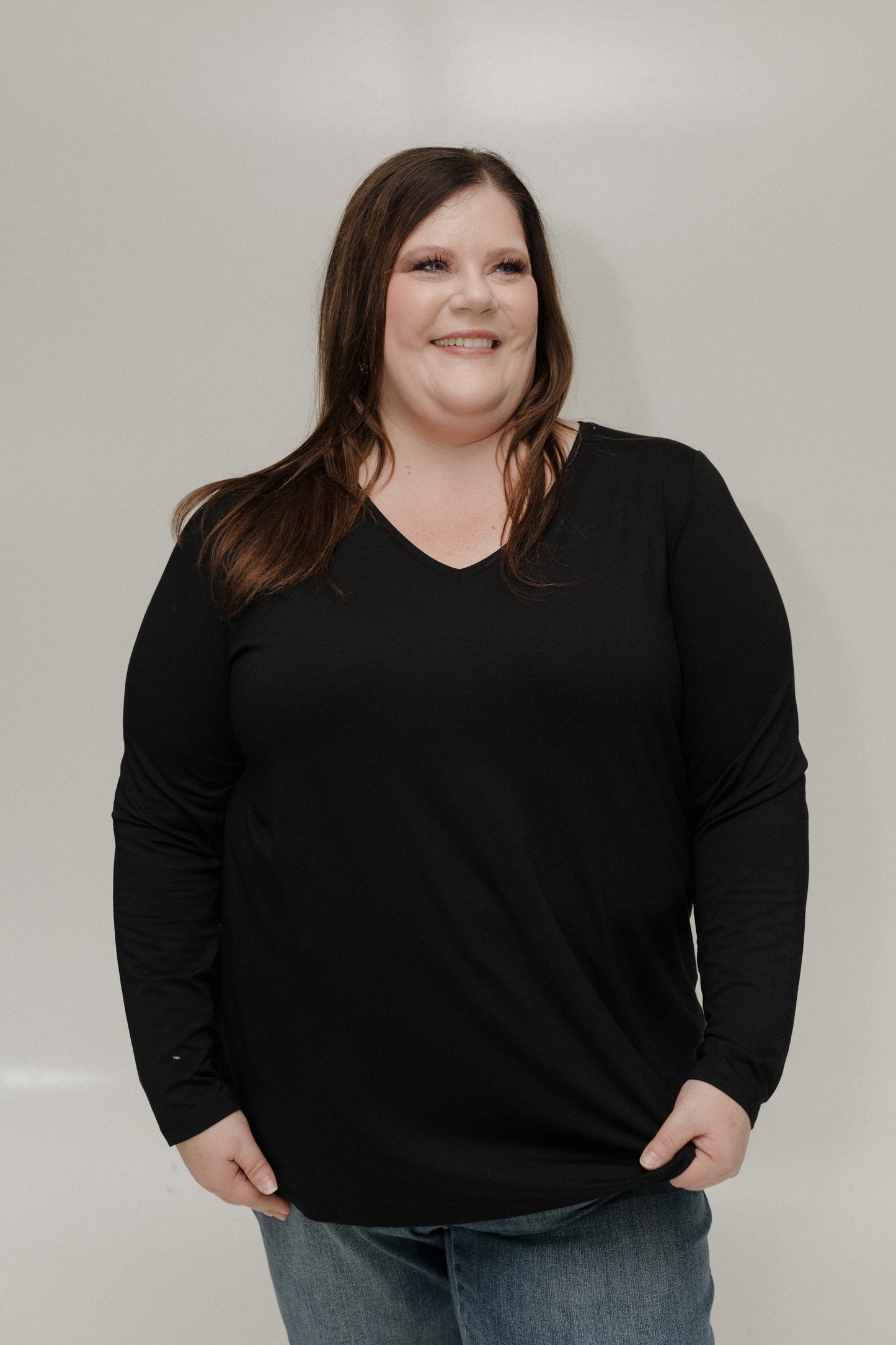 Woman wearing a black long-sleeve shirt against a plain background