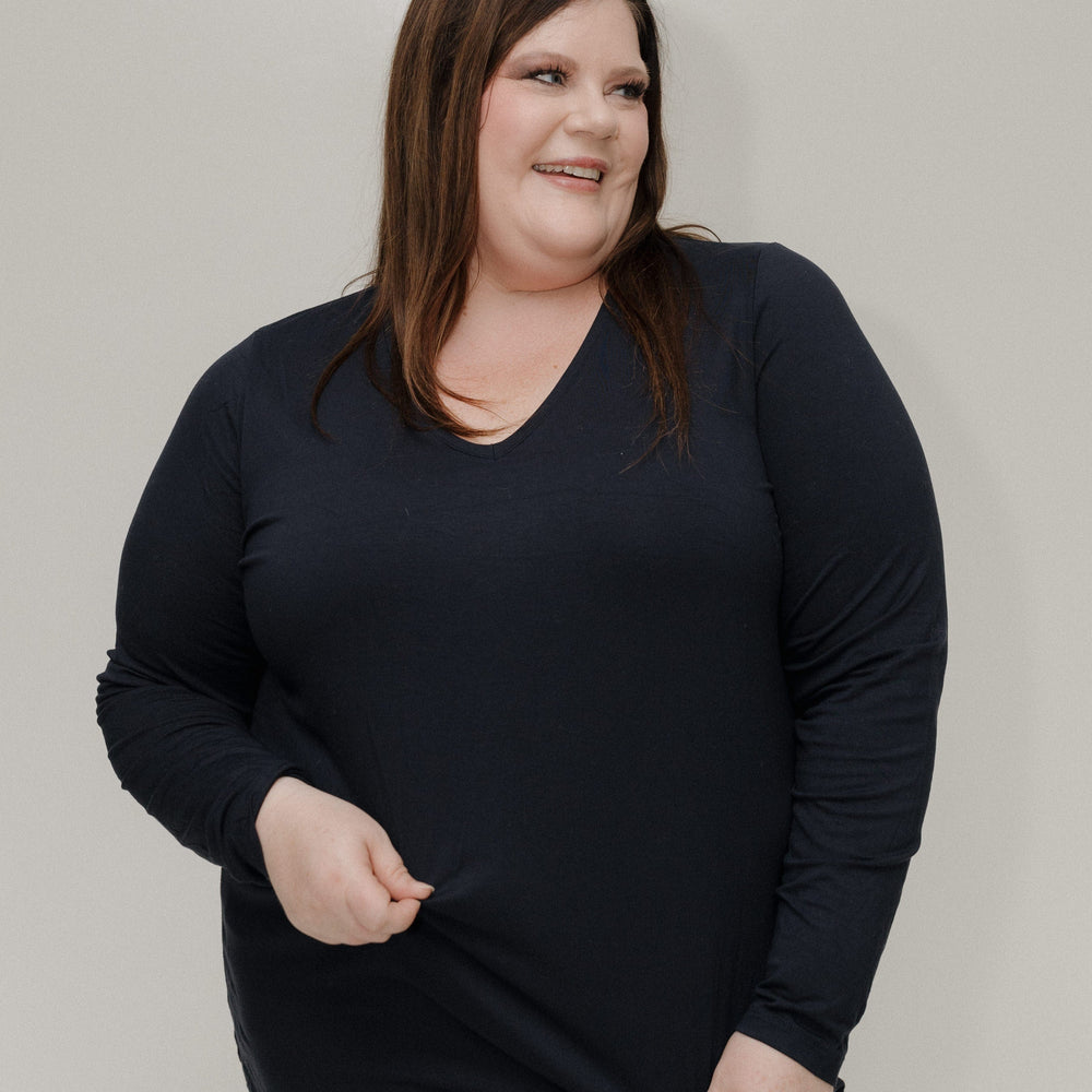 Woman wearing a black long-sleeve shirt against a plain background
