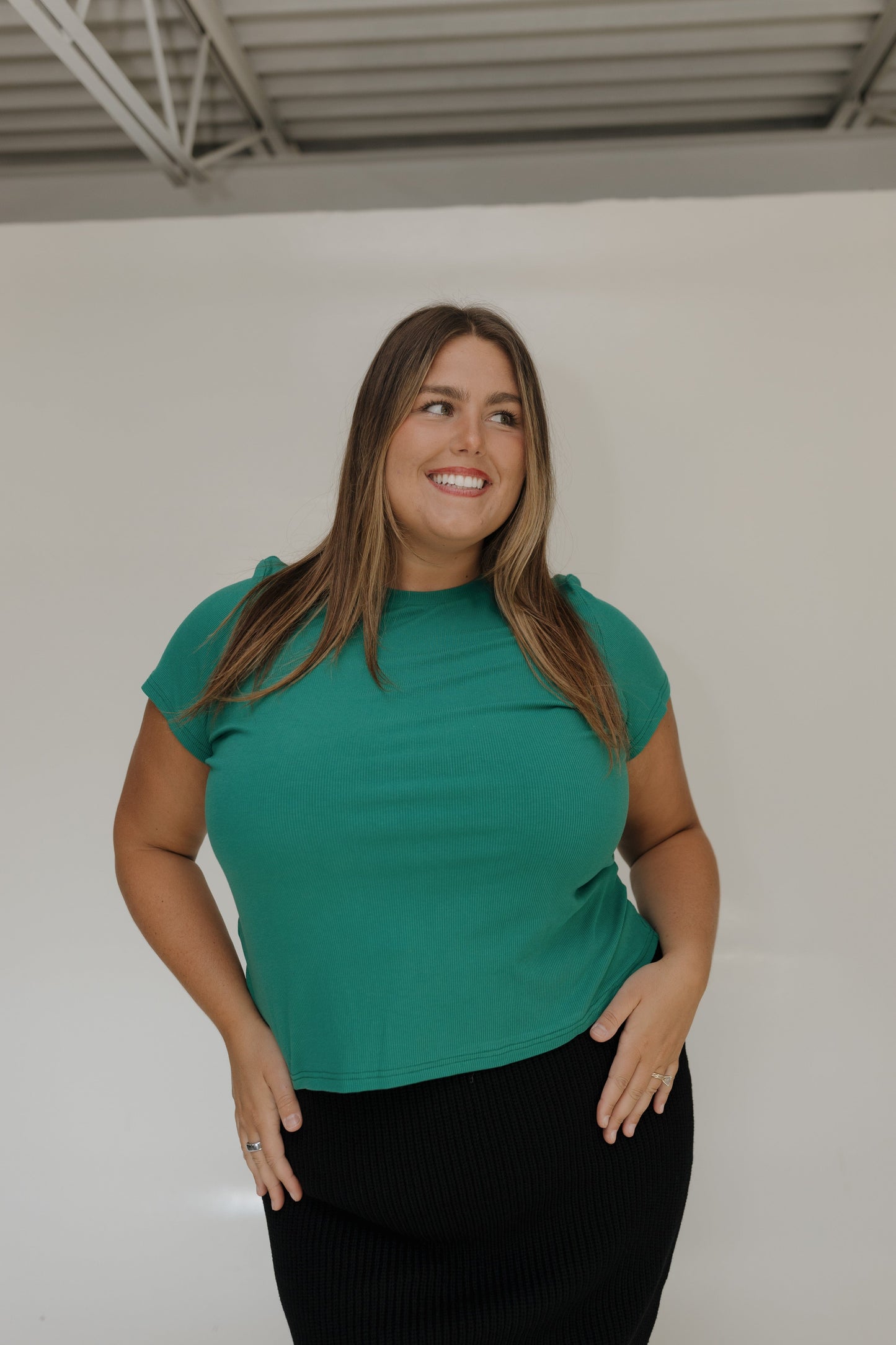 Woman wearing a green top against a white wall