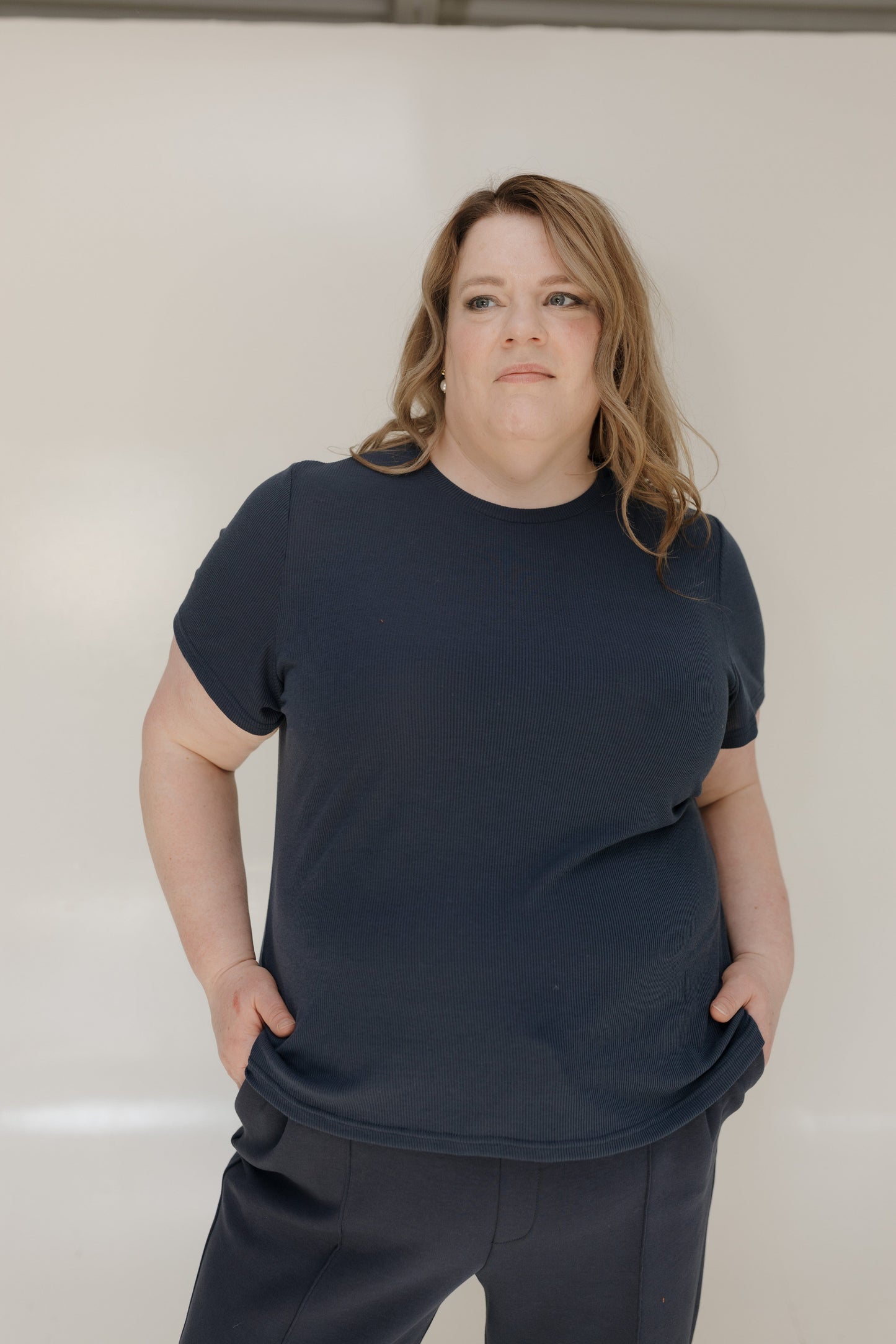 Person wearing a navy blue t-shirt and pants against a plain background