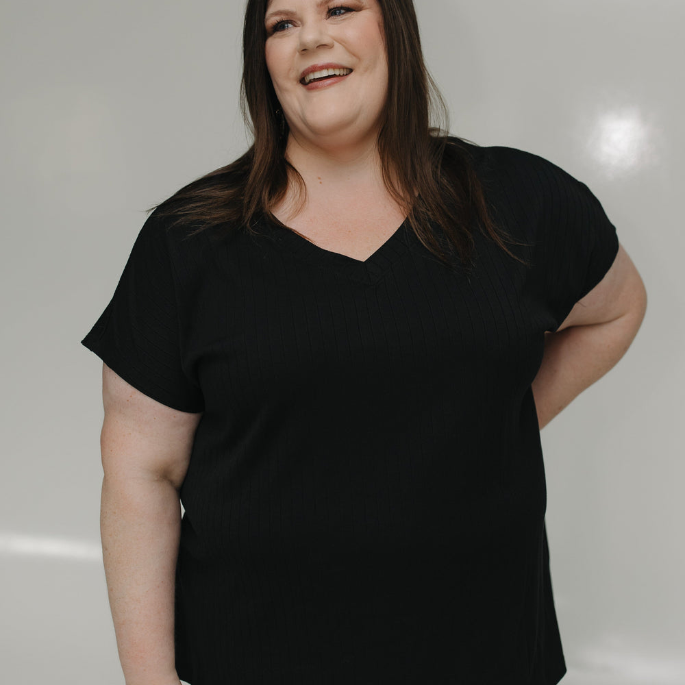 Person wearing a black t-shirt and light blue jeans against a plain background