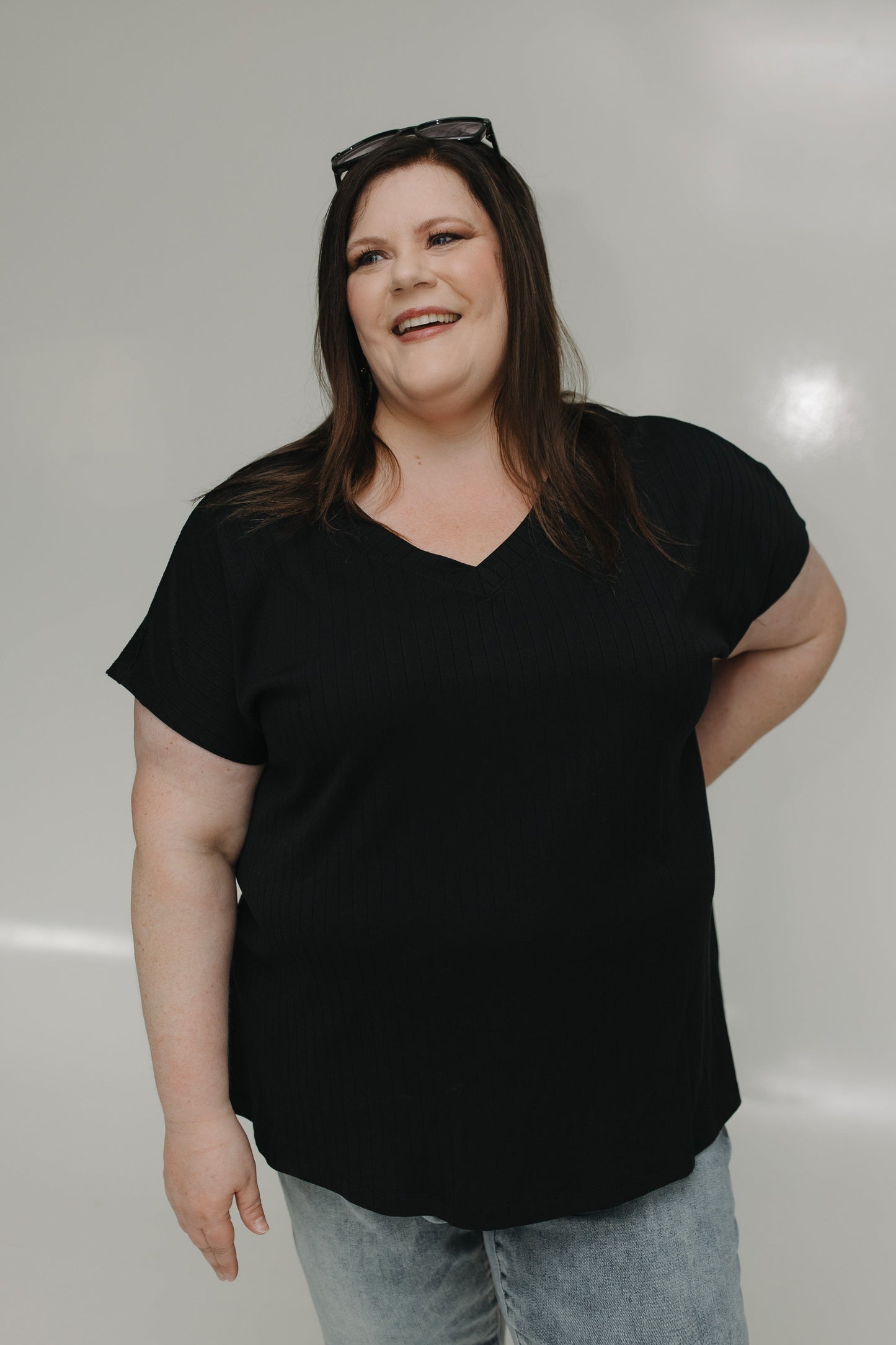 Person wearing a black t-shirt and light blue jeans against a plain background