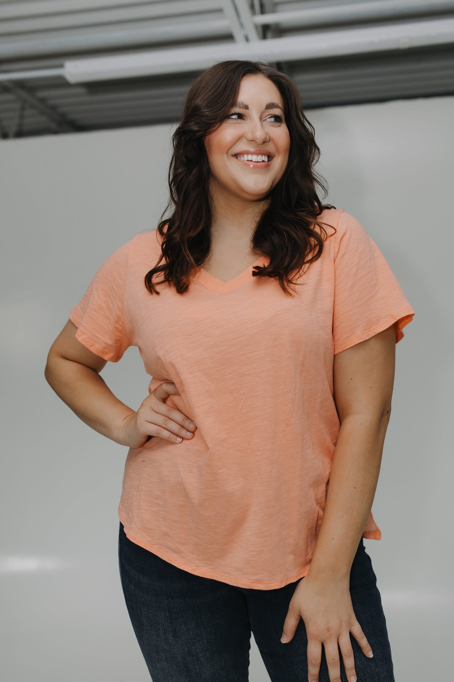 Woman wearing a peach-colored t-shirt and dark pants against a plain background