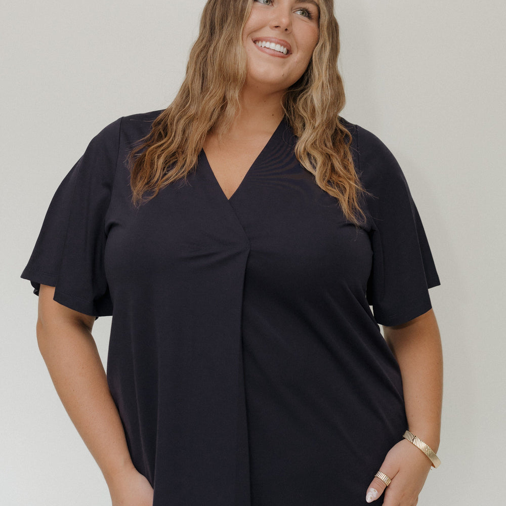 Woman wearing a black top against a plain background