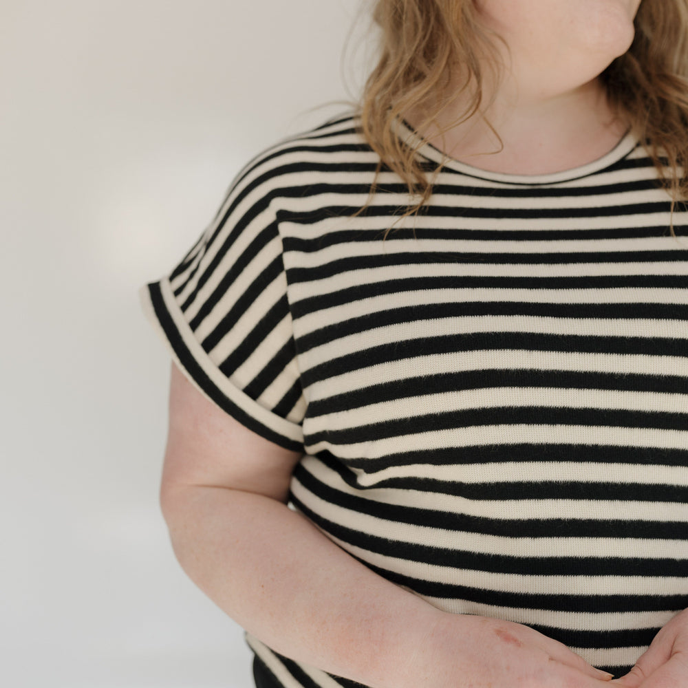 Person wearing a black and white striped shirt against a plain background