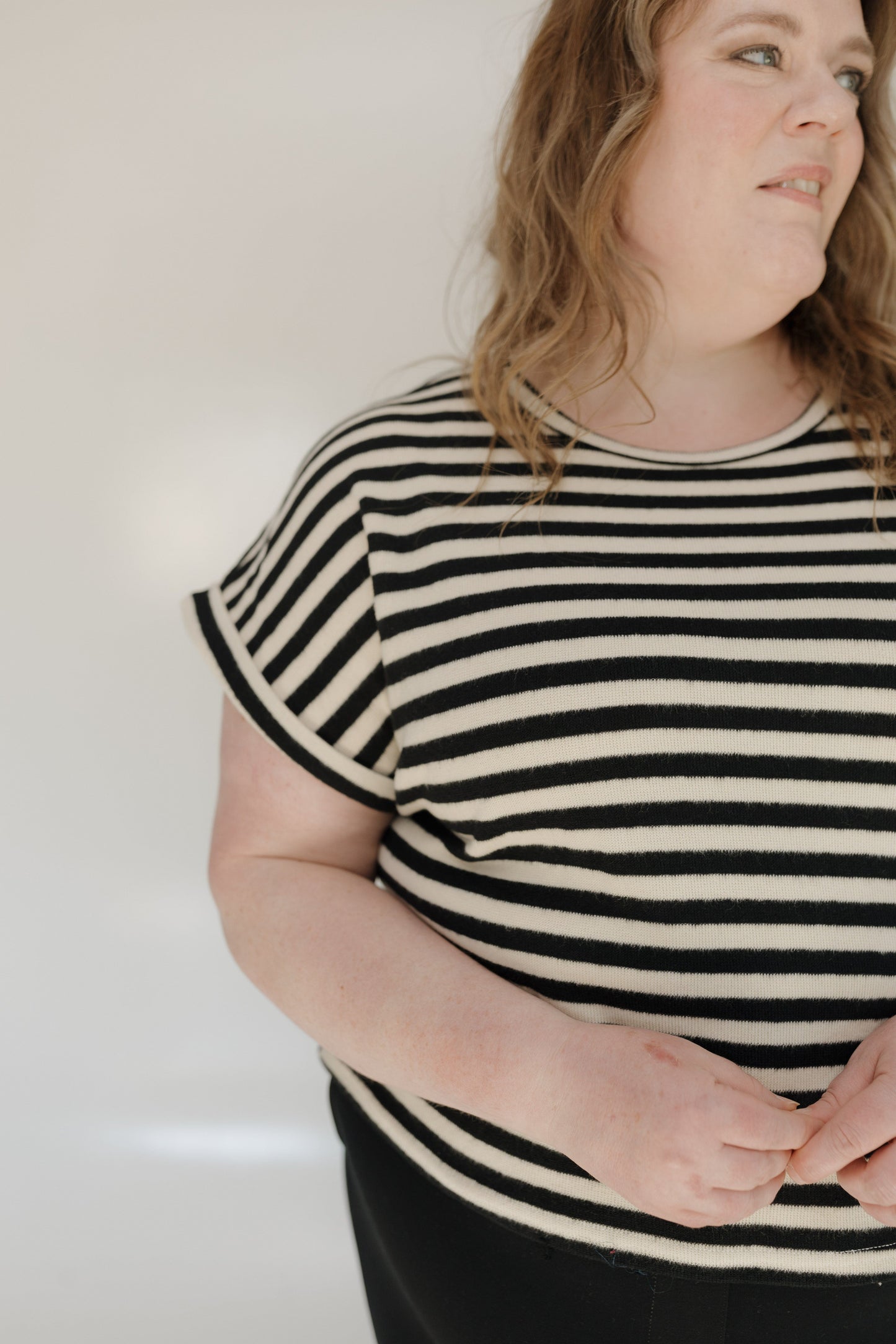 Person wearing a black and white striped shirt against a plain background