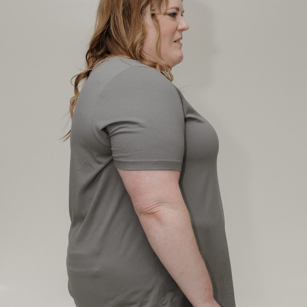 Woman wearing a gray t-shirt against a plain background