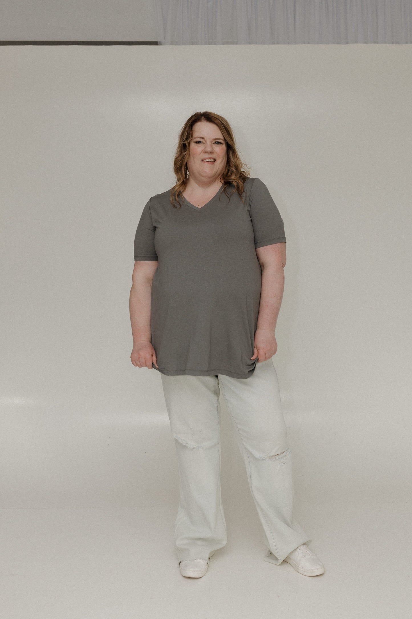 Person wearing a gray t-shirt and light-colored pants on a plain background