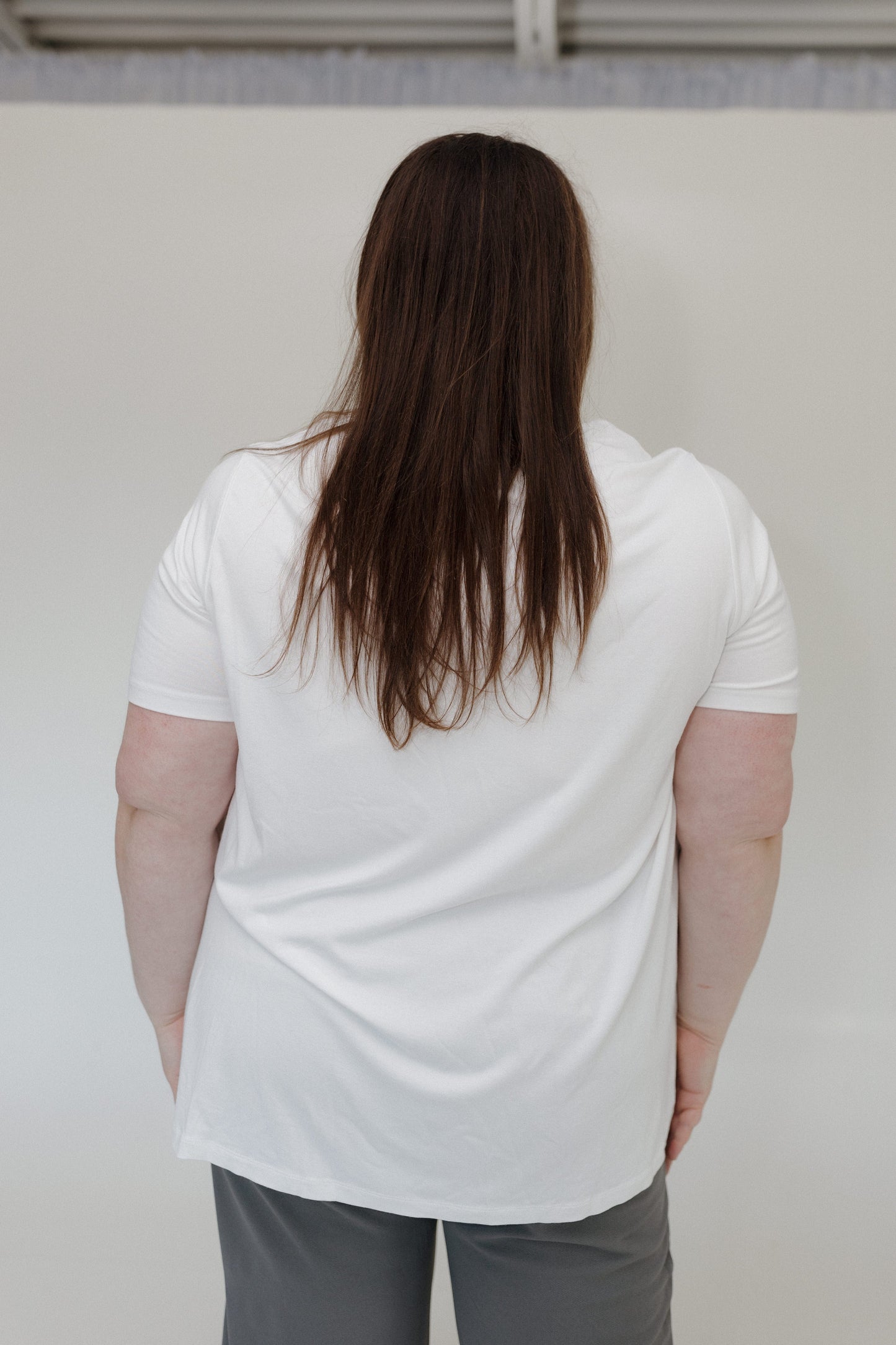 Person wearing a white t-shirt and gray pants against a plain background