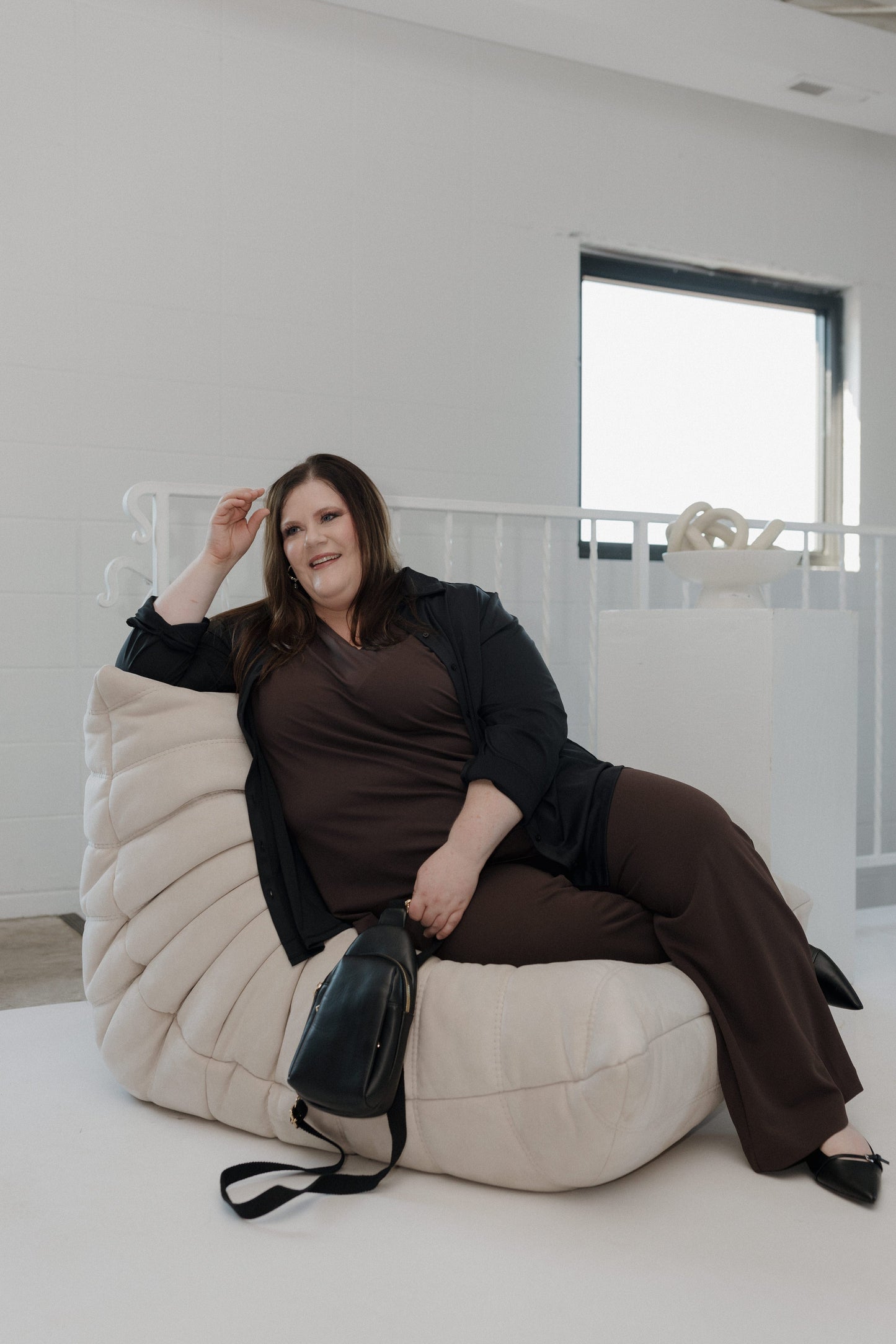 Woman sitting on a bean bag chair in a minimalistic room.