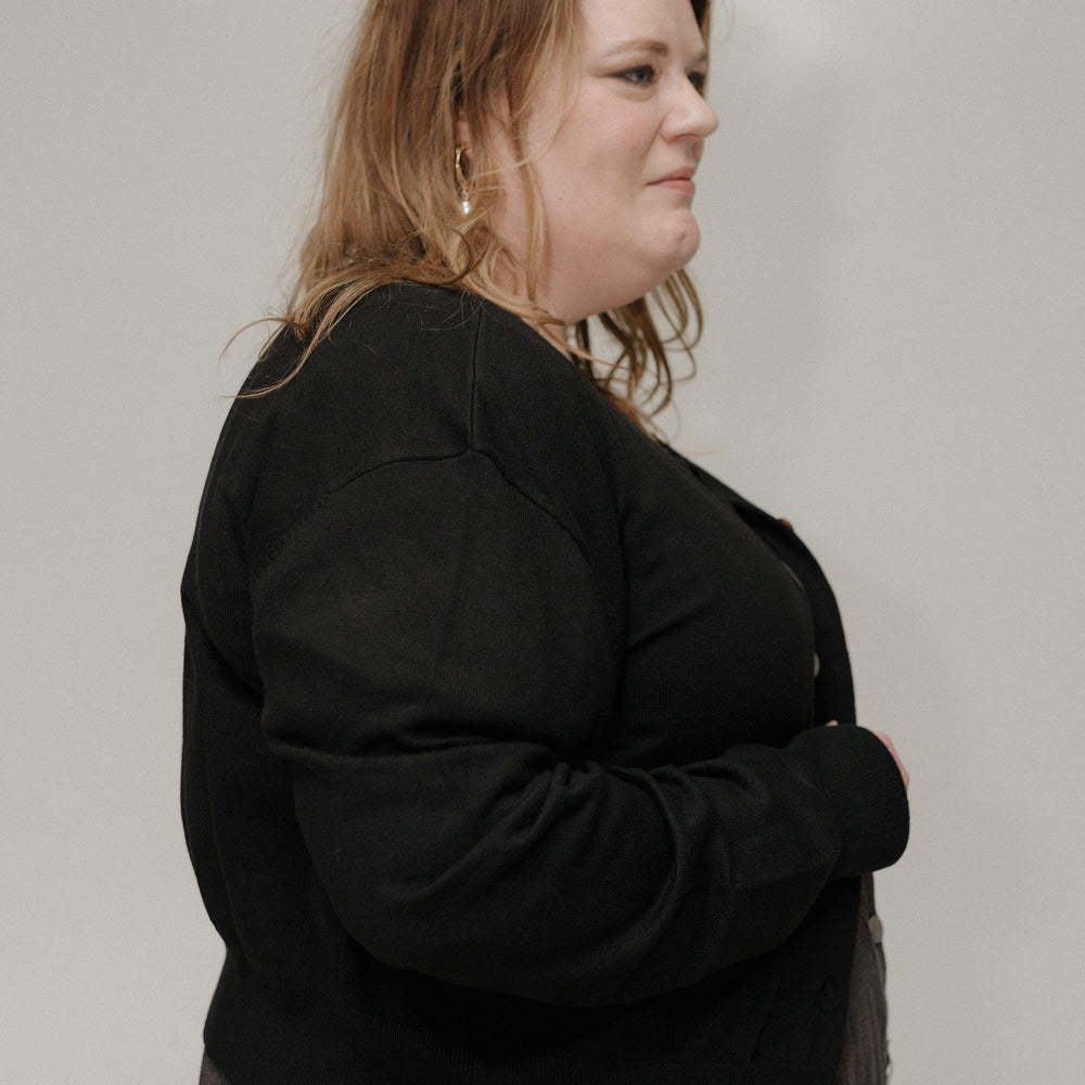 Woman wearing a black sweater against a plain background