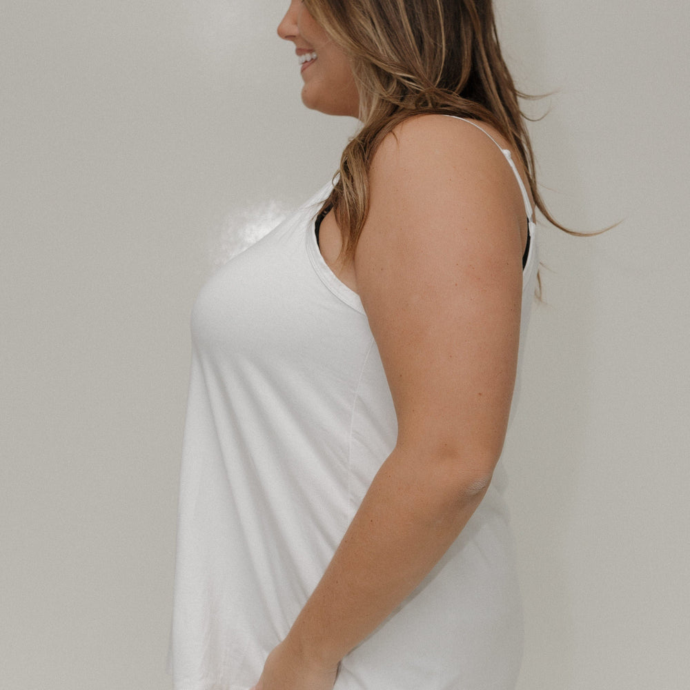 Woman wearing a white sleeveless top against a plain background