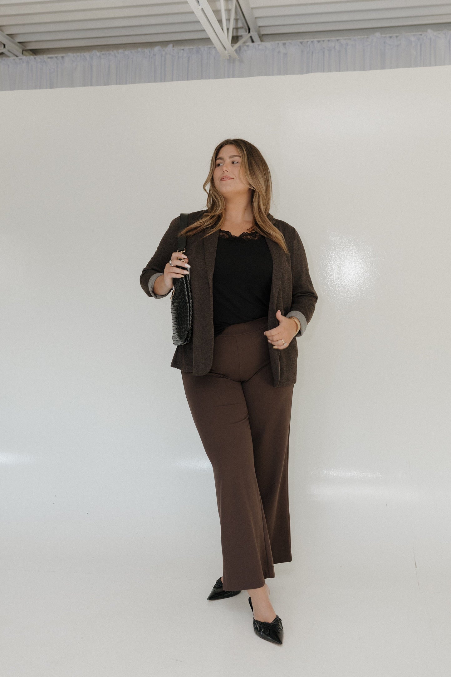 Woman wearing a brown suit standing against a white wall