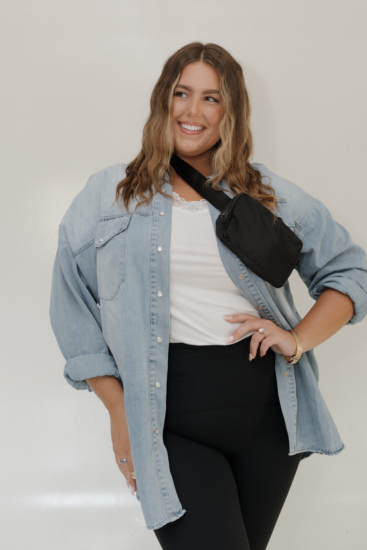 Woman wearing a denim jacket and black pants with a white background