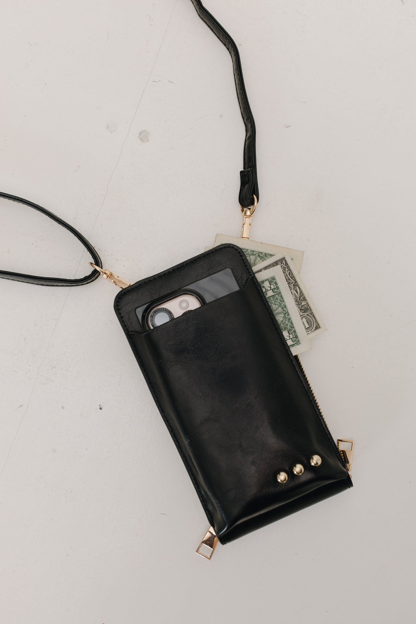 Black phone pouch with a strap on a light gray surface