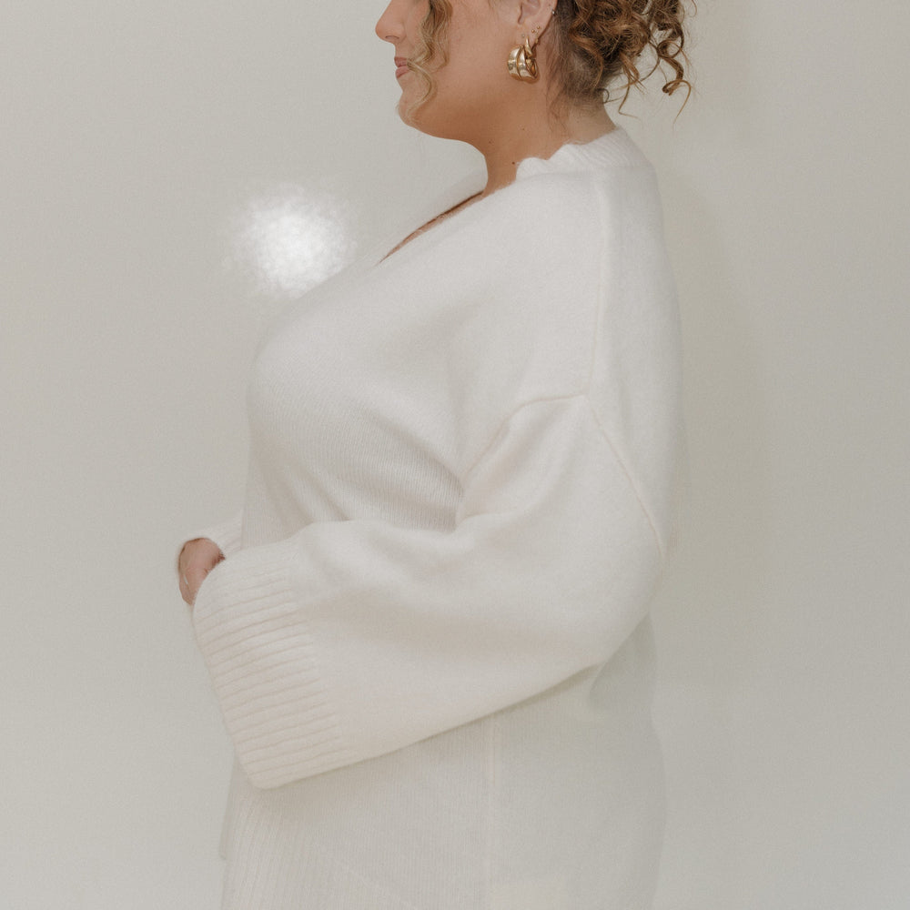 Woman wearing a white sweater and leopard print underwear against a plain background