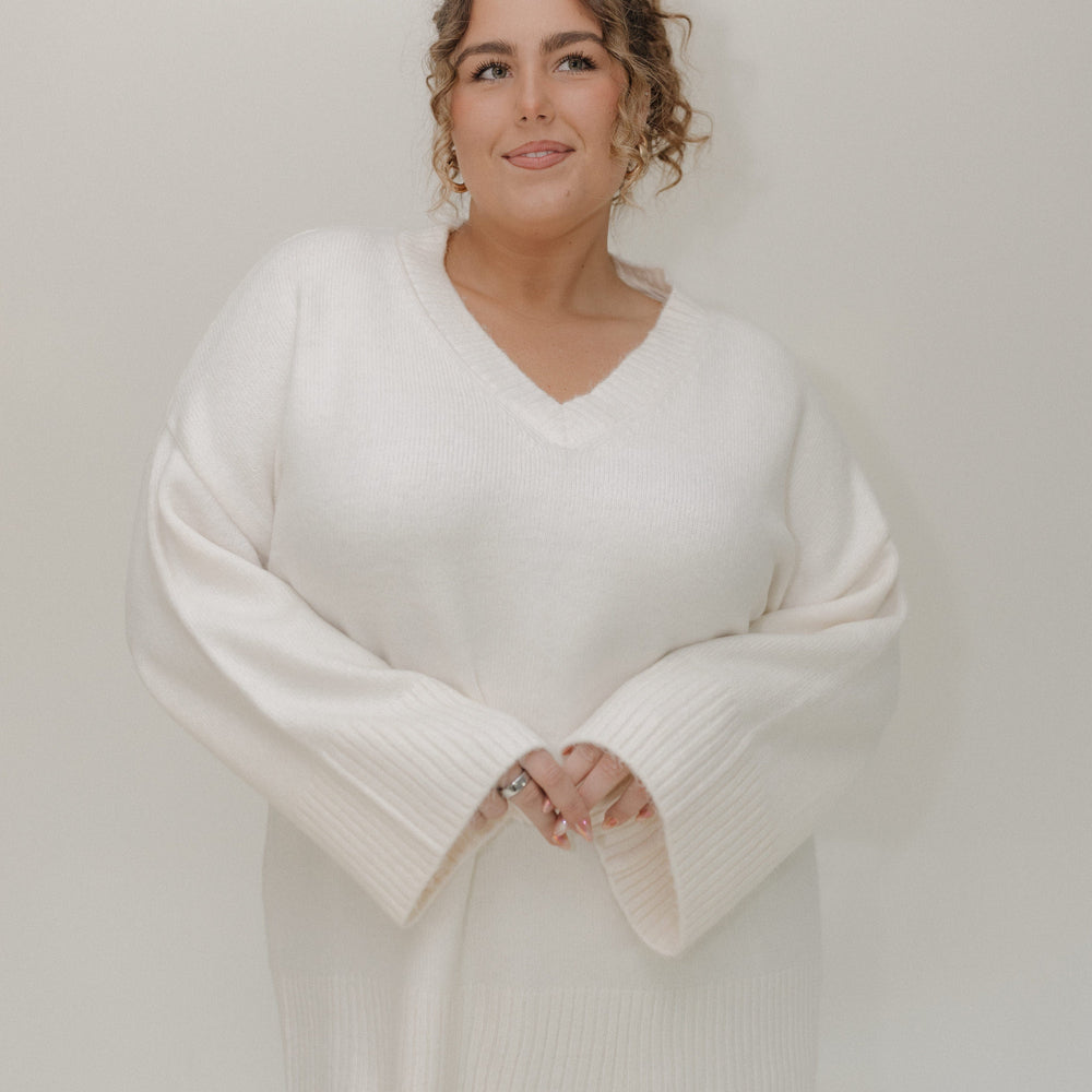 Woman wearing a white sweater and leopard print skirt against a plain background