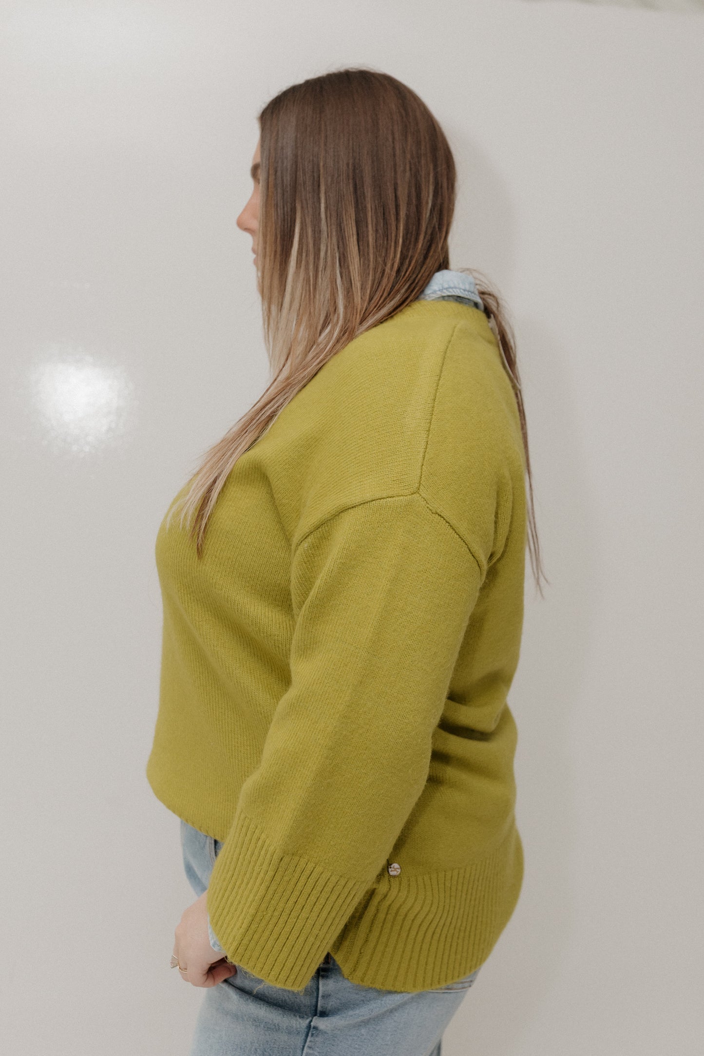 Person wearing a green sweater against a plain background
