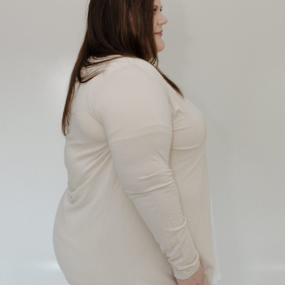 Woman wearing a beige long-sleeve top against a white background