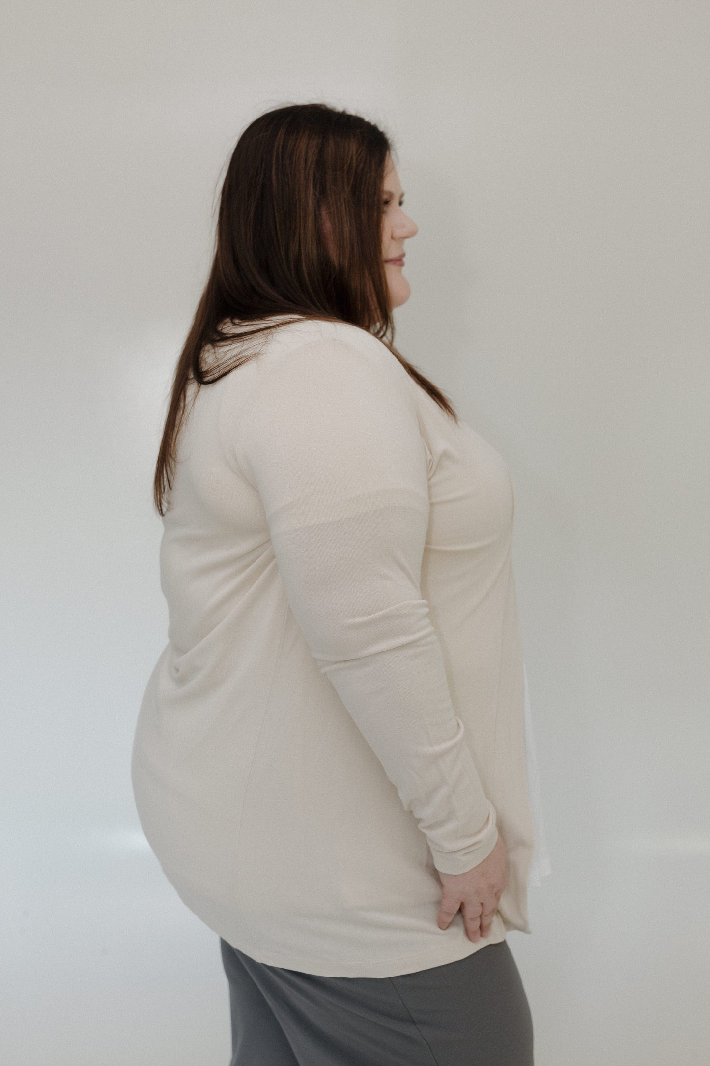 Woman wearing a beige long-sleeve top against a white background