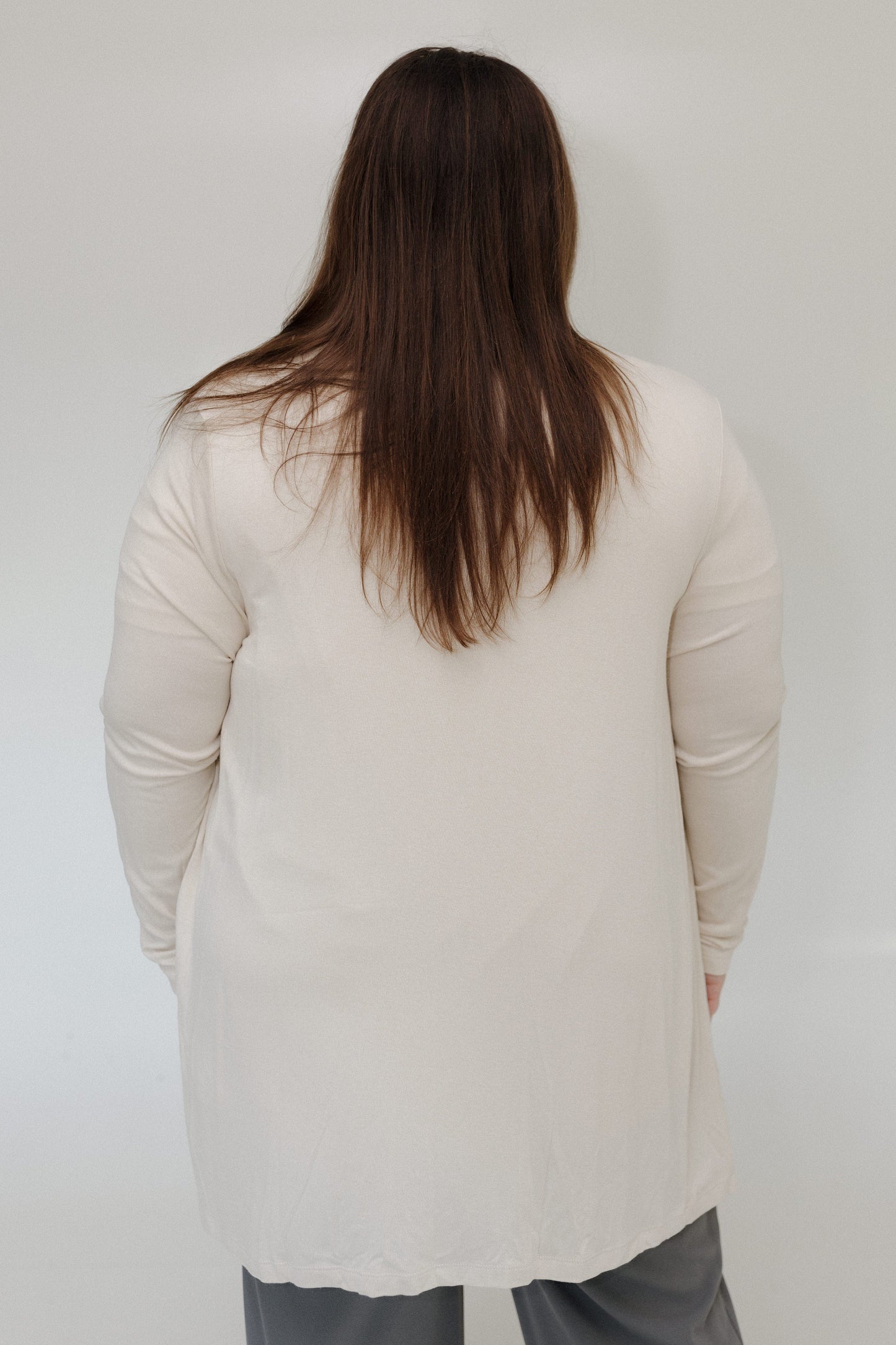 Person wearing a beige cardigan against a plain background