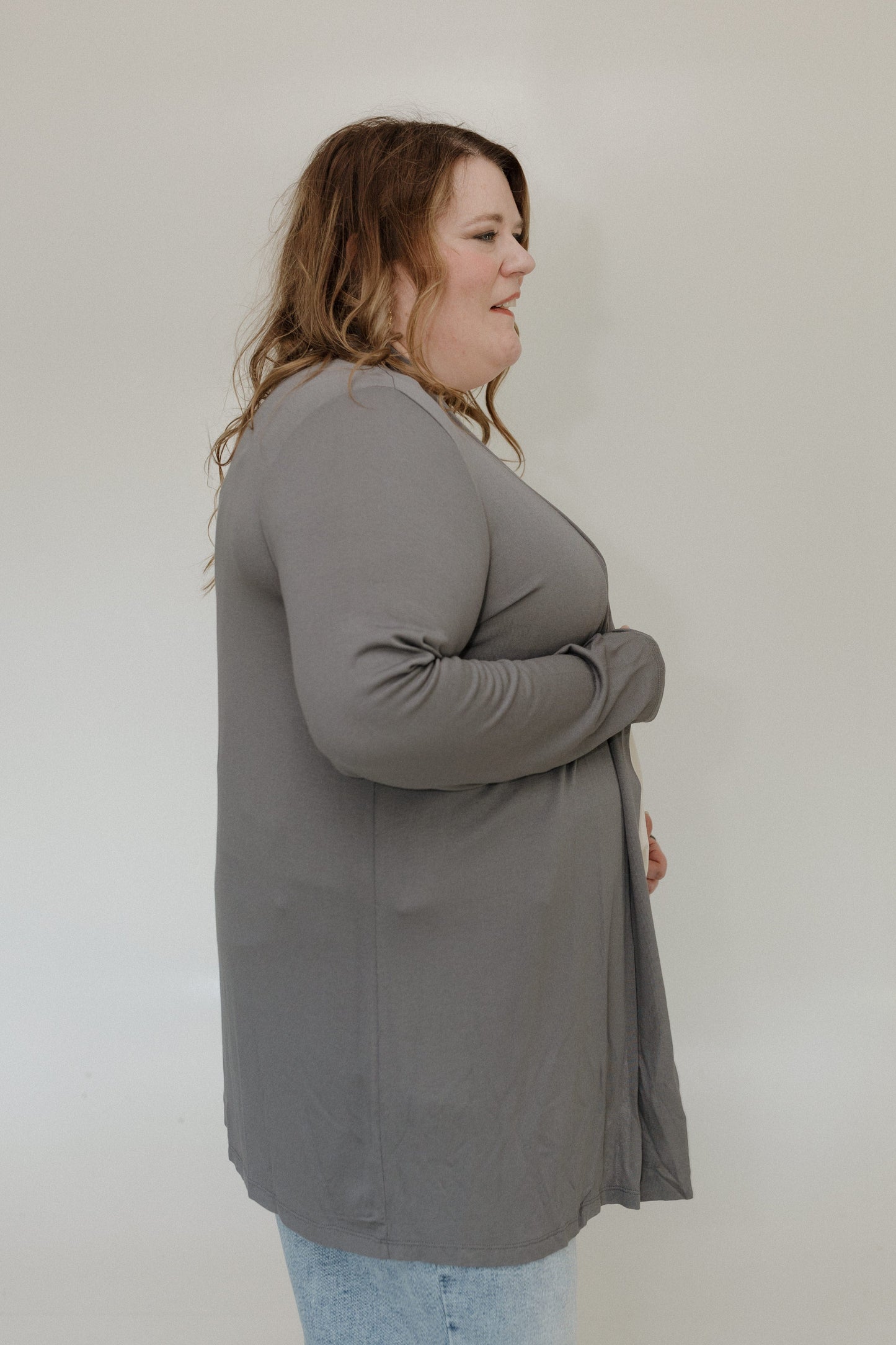 Woman wearing a gray cardigan against a white background