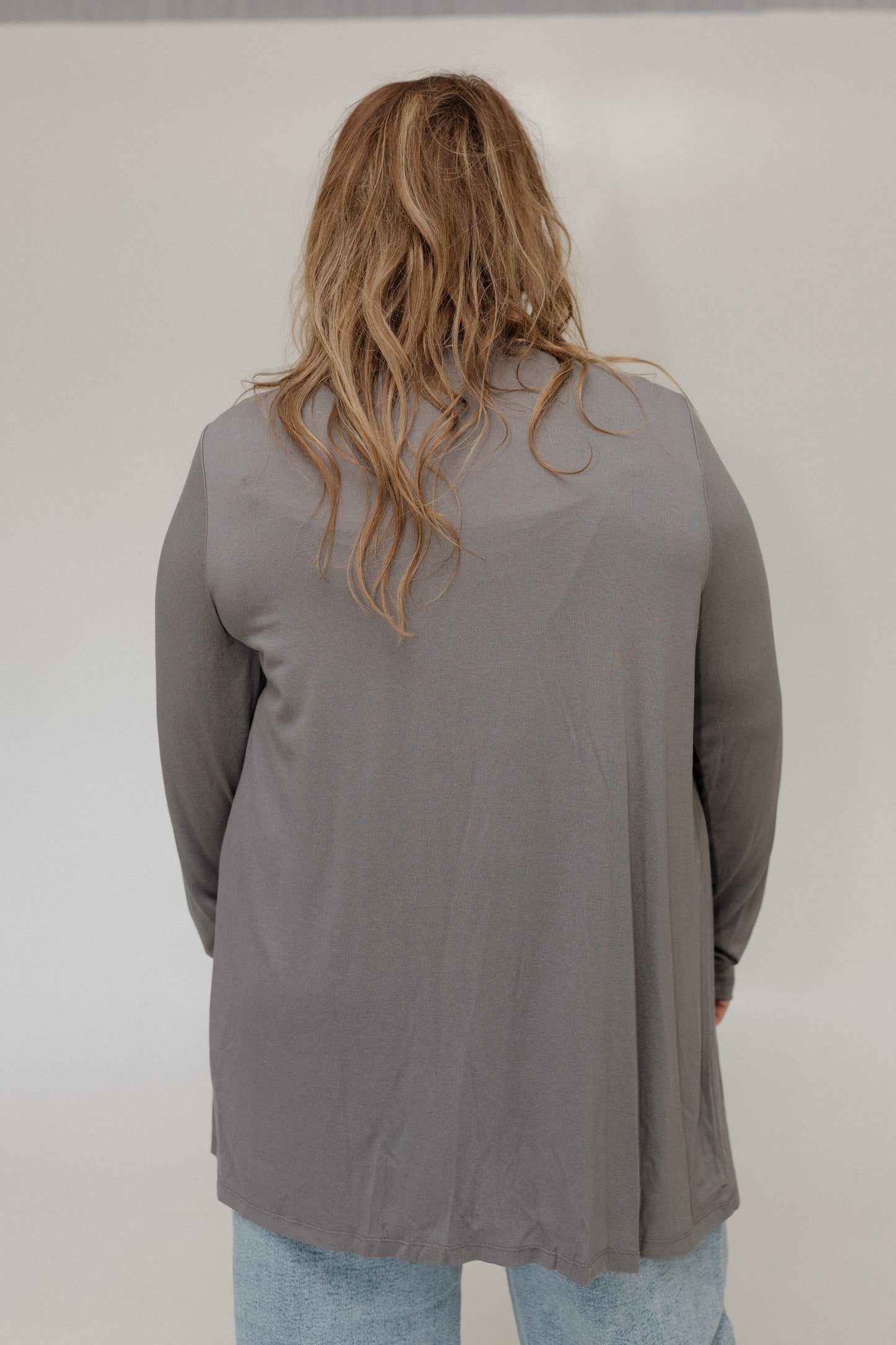 Person wearing a gray long-sleeve top against a plain background