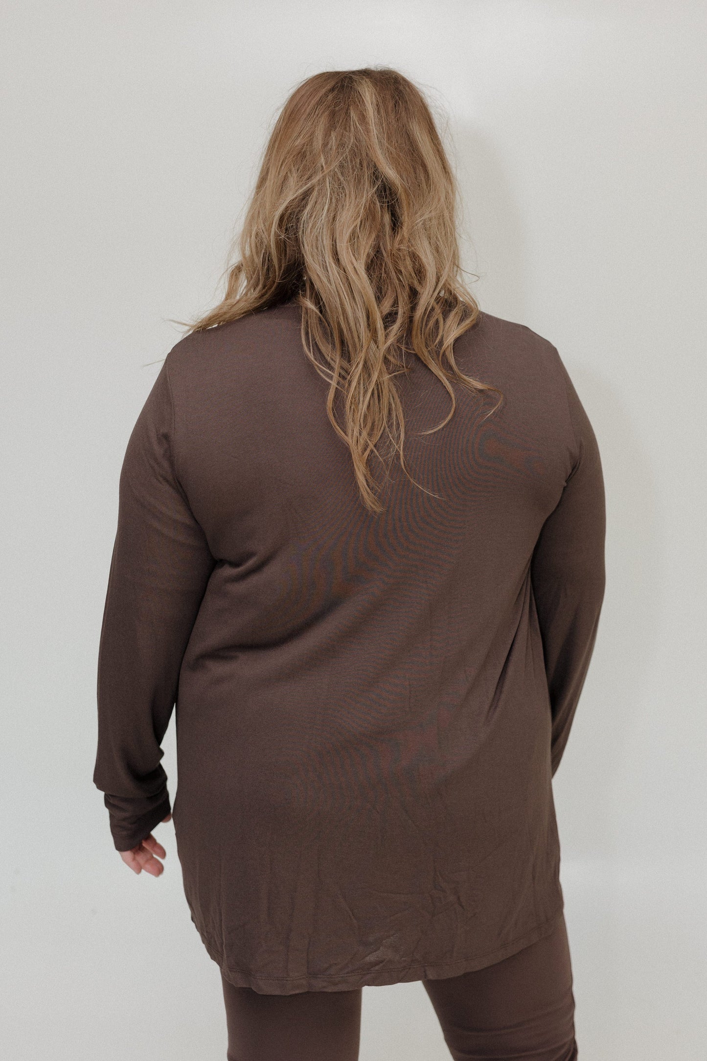Person wearing a brown long-sleeve top against a white background