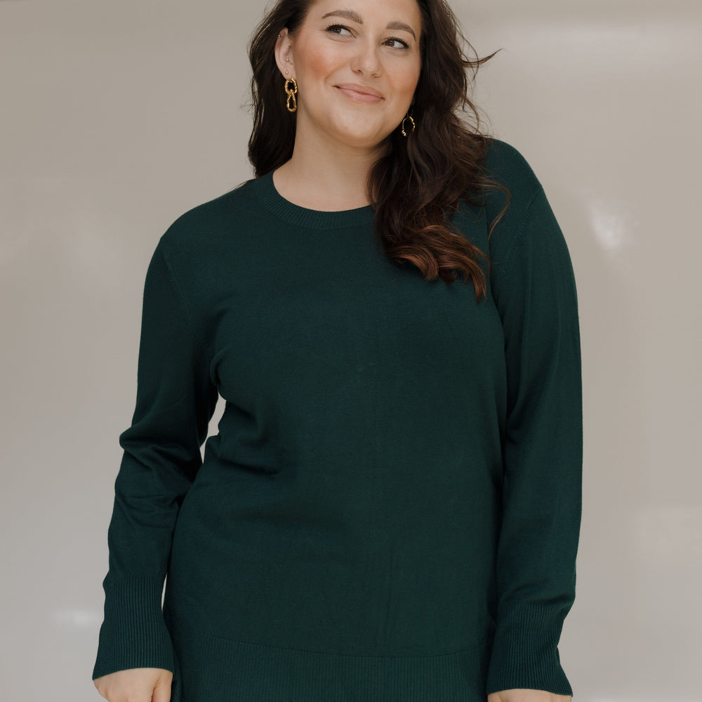 Woman wearing a dark green sweater against a plain background