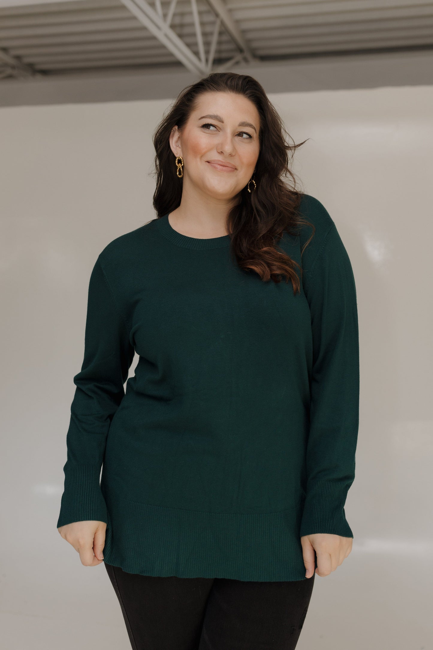 Woman wearing a dark green sweater against a plain background