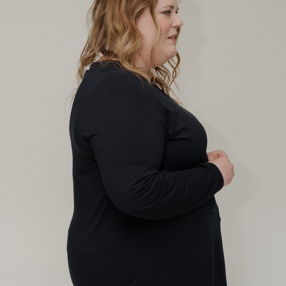 Person wearing a black sweater and light blue jeans against a plain background