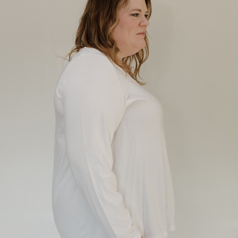 Person wearing a white long-sleeve shirt against a plain background
