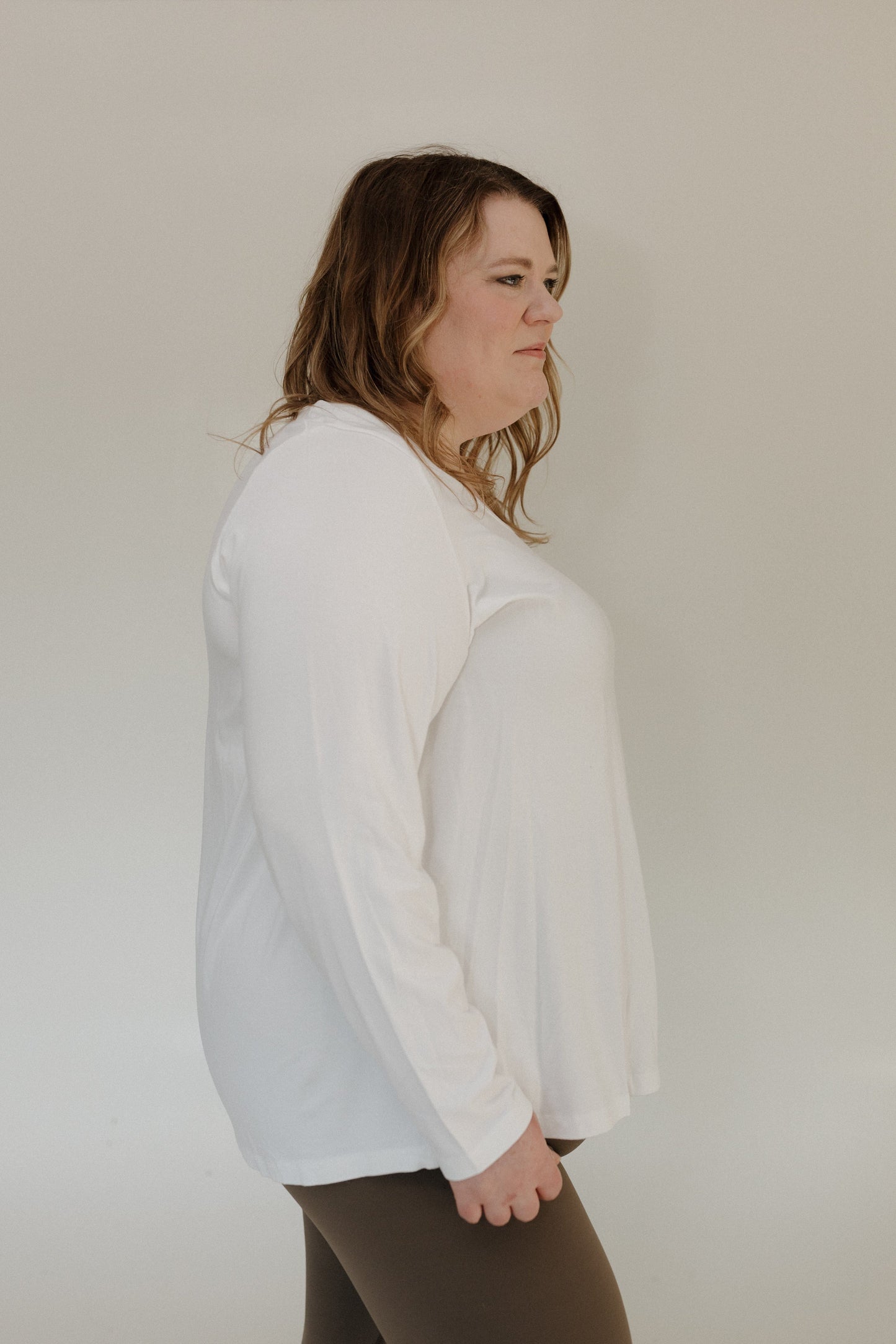 Person wearing a white long-sleeve shirt against a plain background