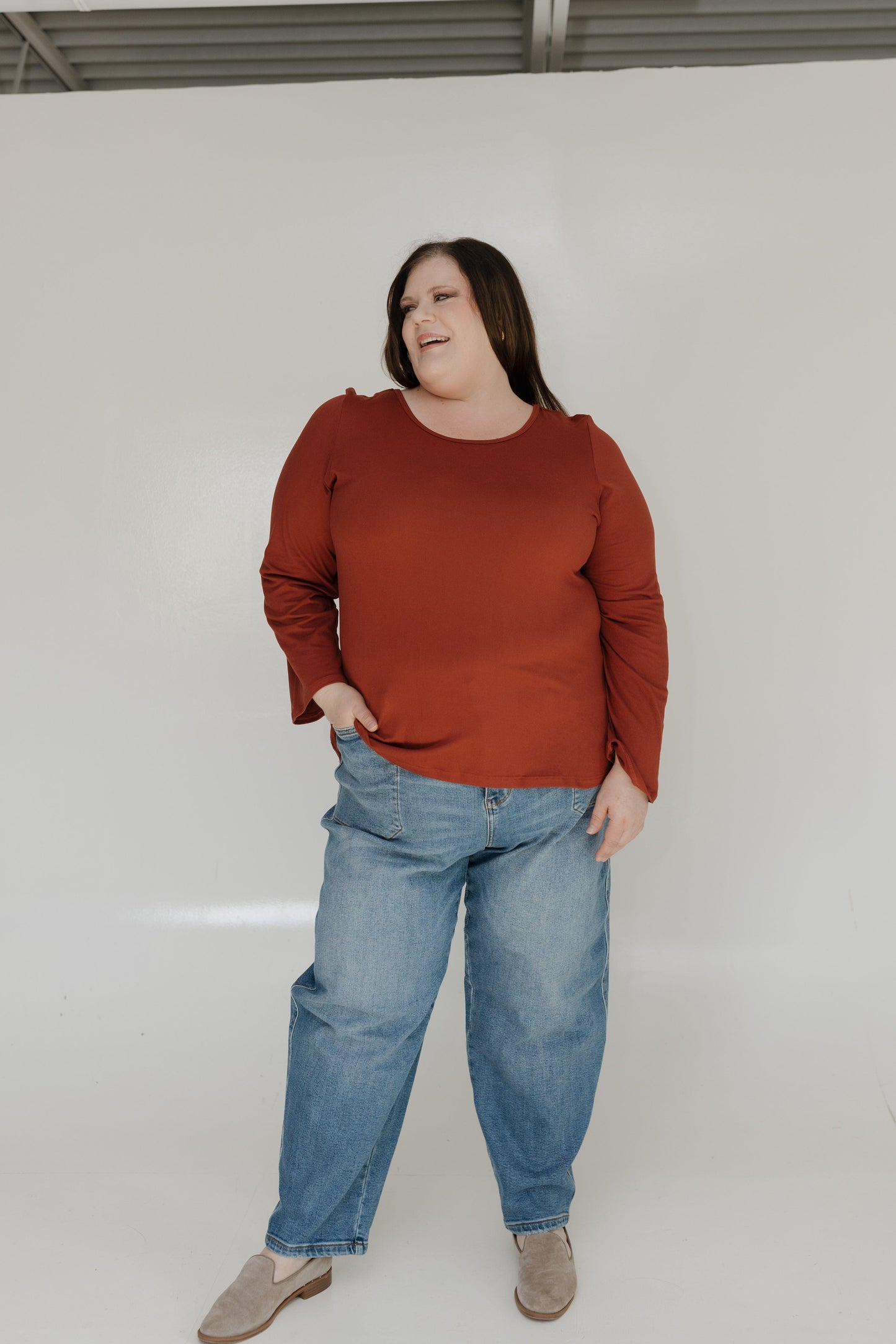 Person wearing a red sweater and blue jeans against a white background