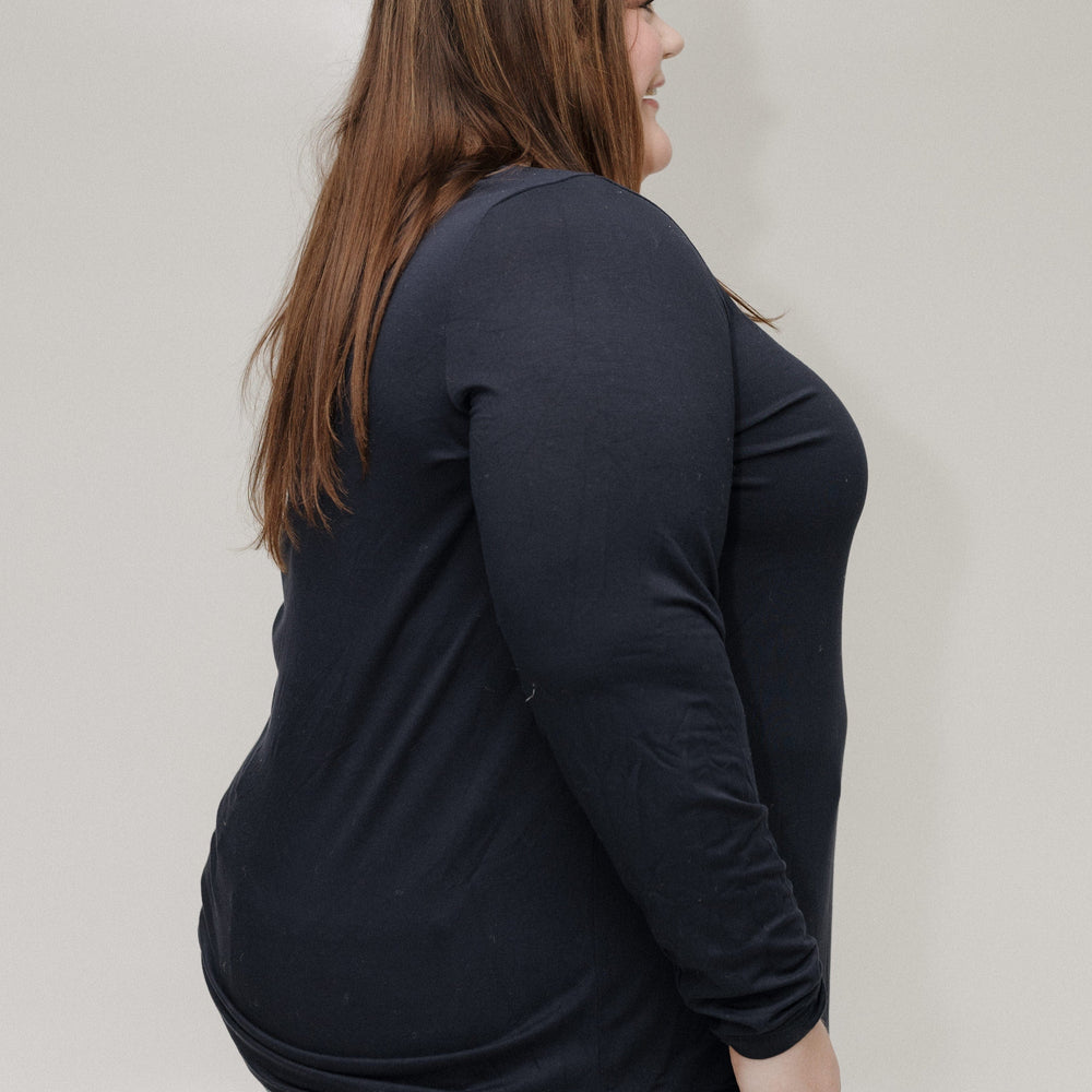 Person wearing a black long-sleeve shirt and blue jeans against a plain background