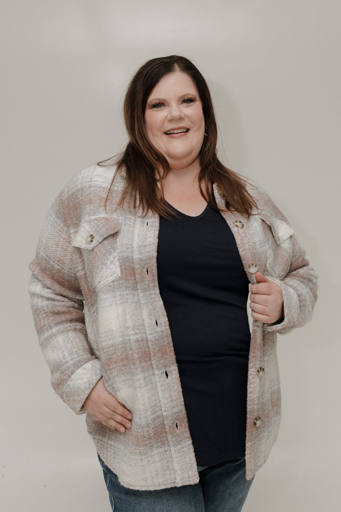 Woman wearing a plaid jacket over a black top against a plain background