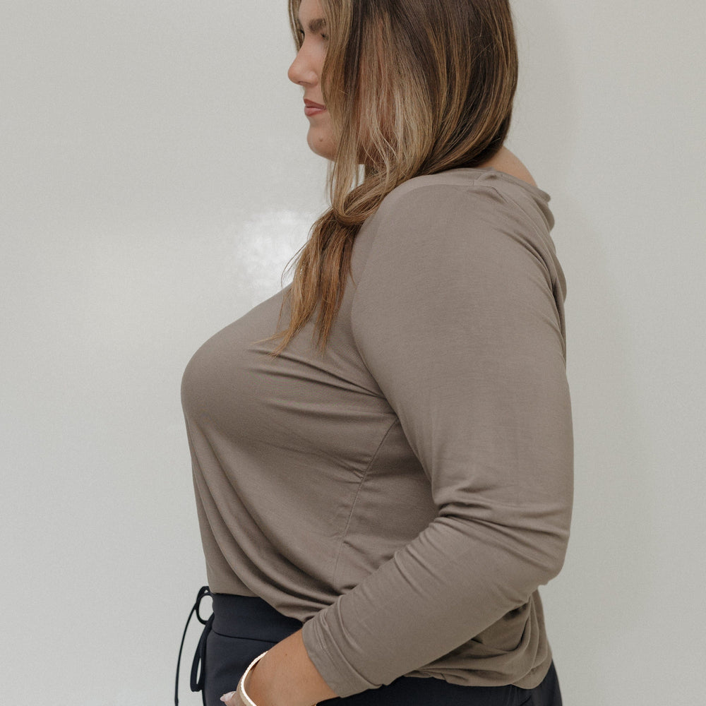 Woman wearing a beige long-sleeve top against a plain background
