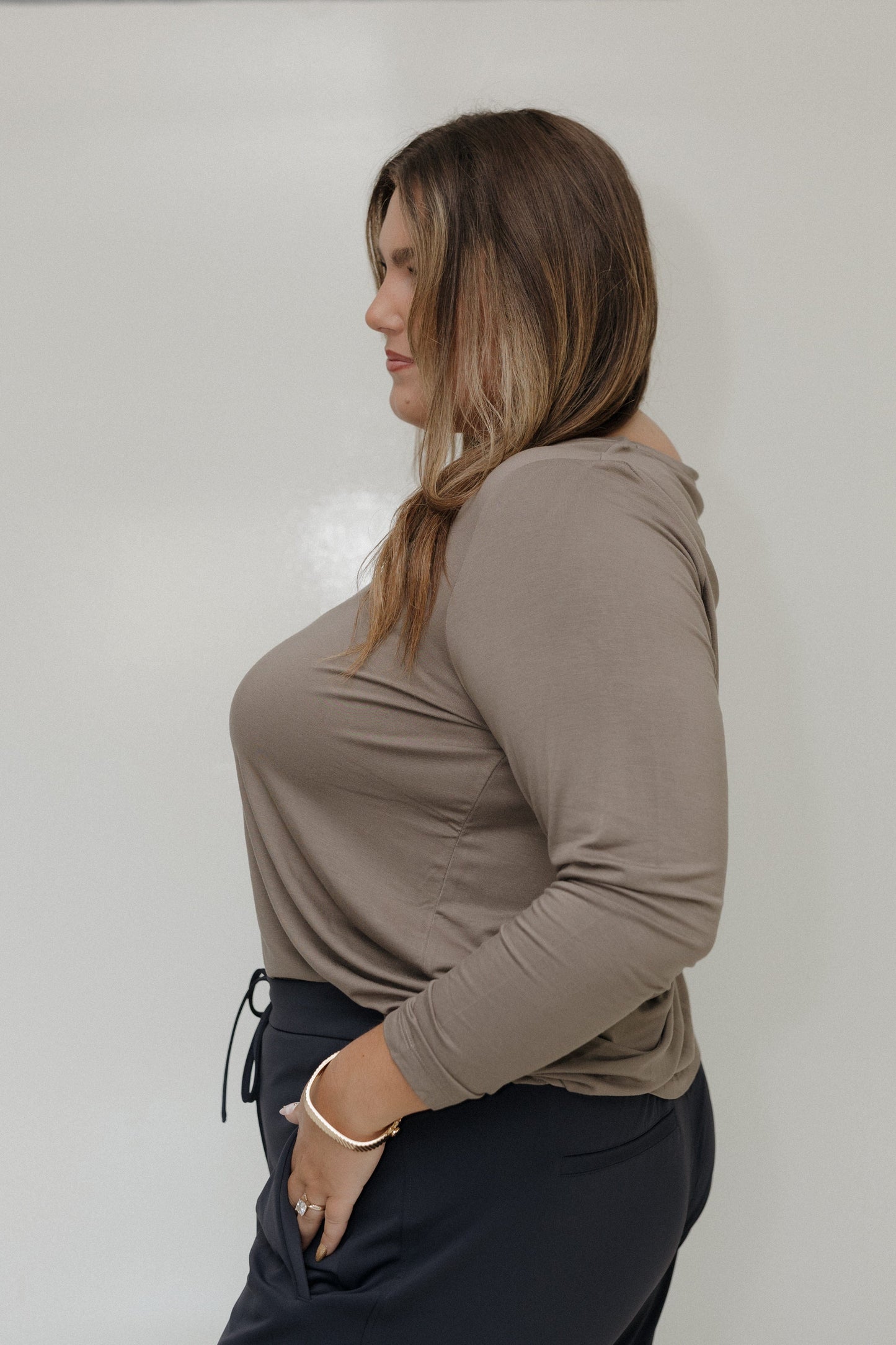 Woman wearing a beige long-sleeve top against a plain background