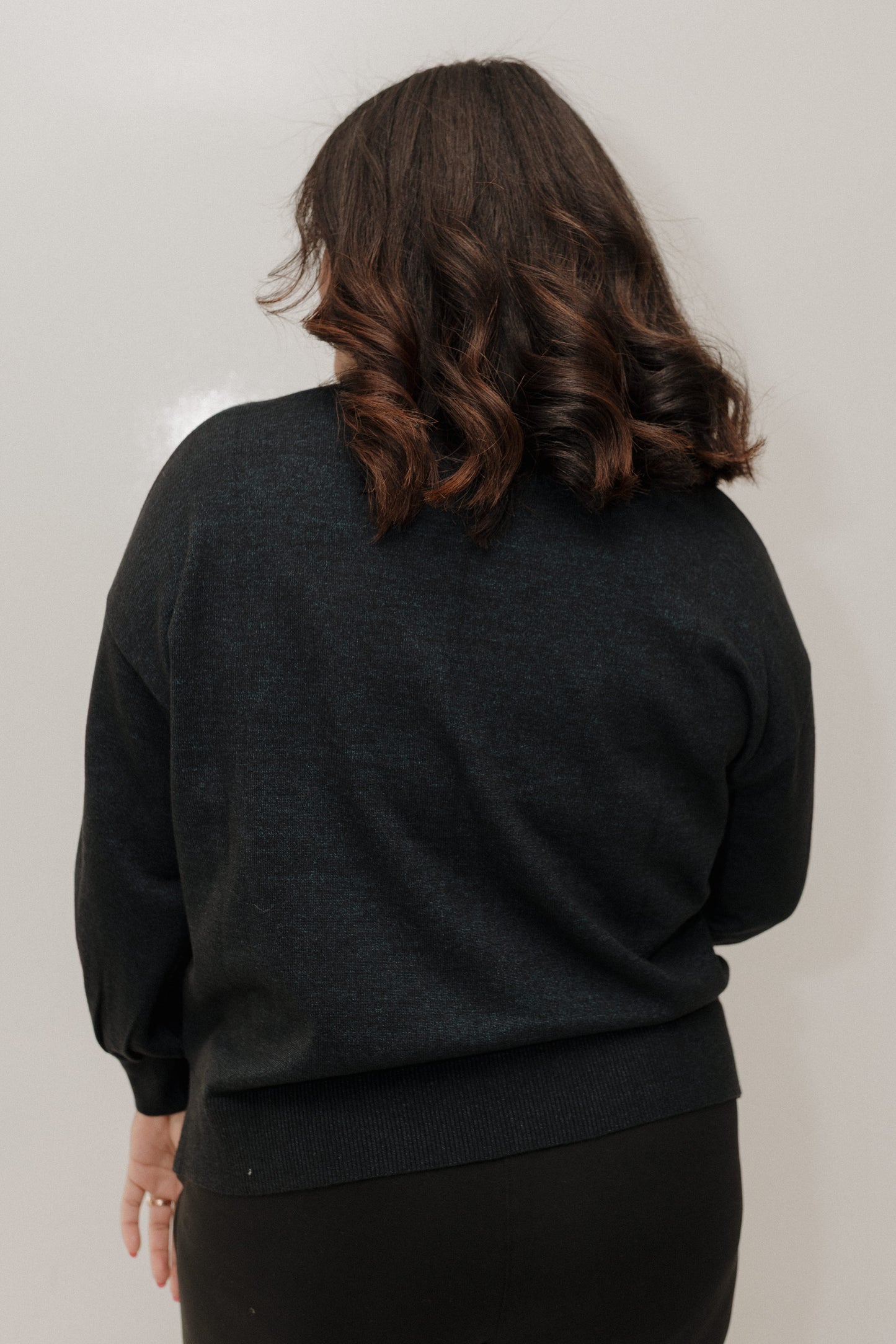 Person wearing a dark gray sweater against a plain background