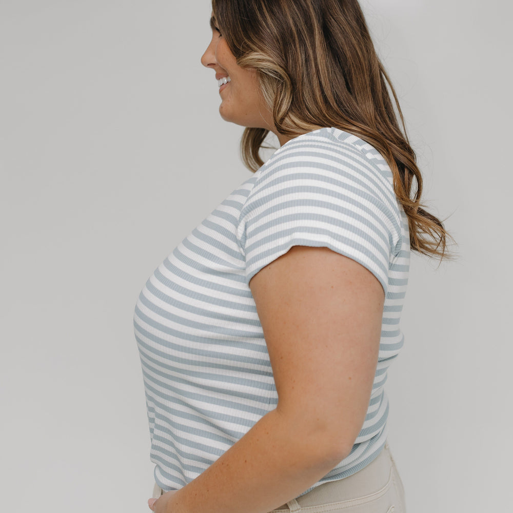 Woman wearing a striped shirt and beige pants against a white background
