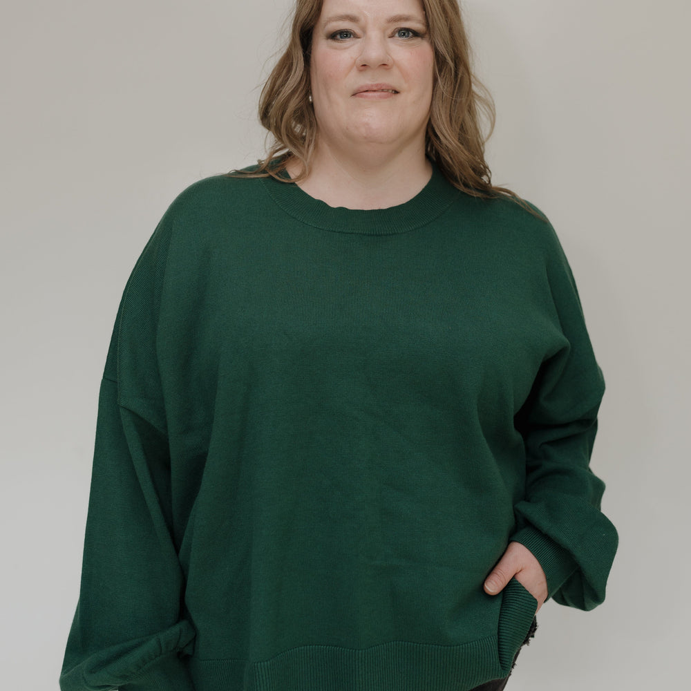 Person wearing a green sweater against a plain background