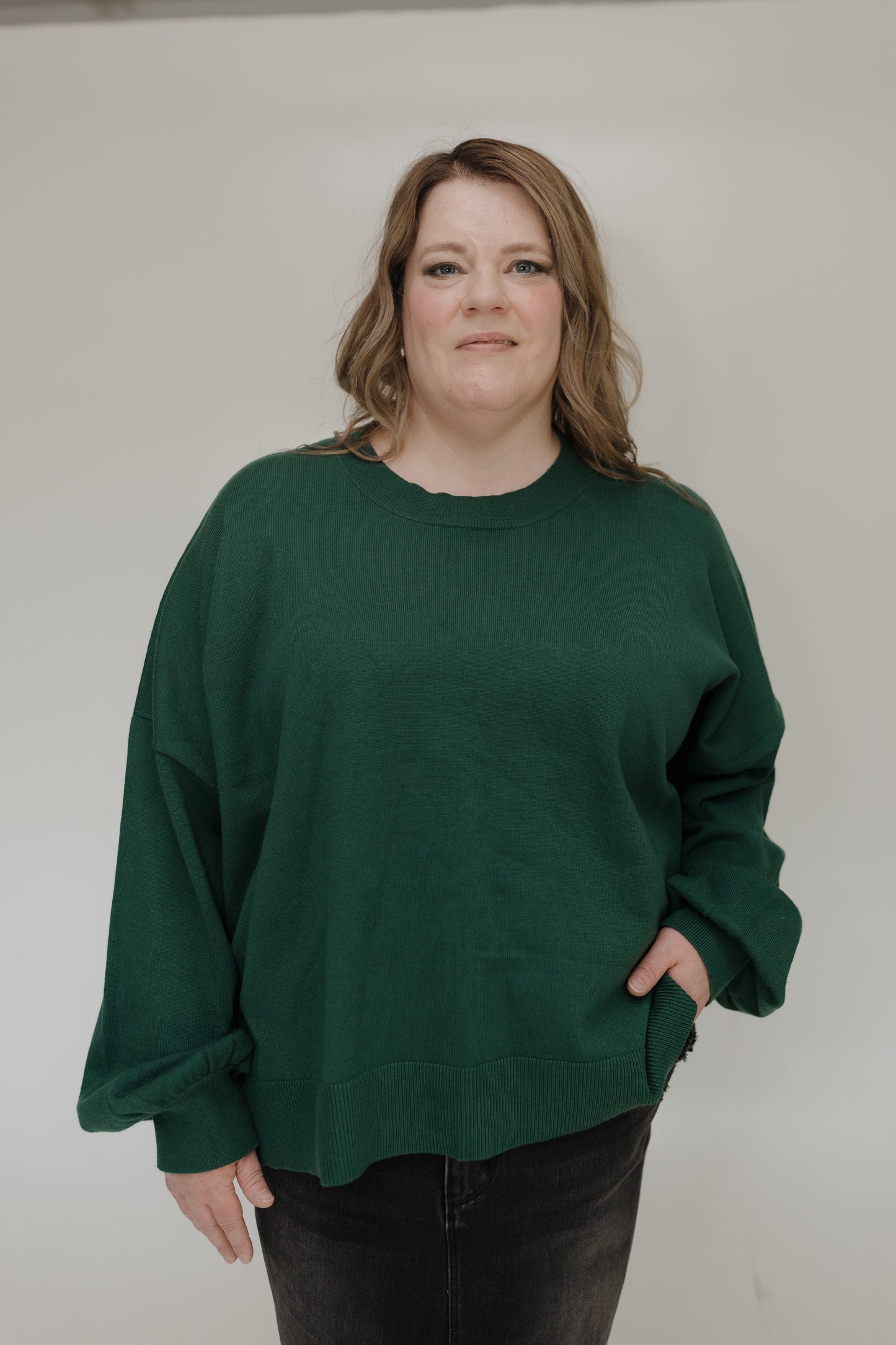 Person wearing a green sweater against a plain background