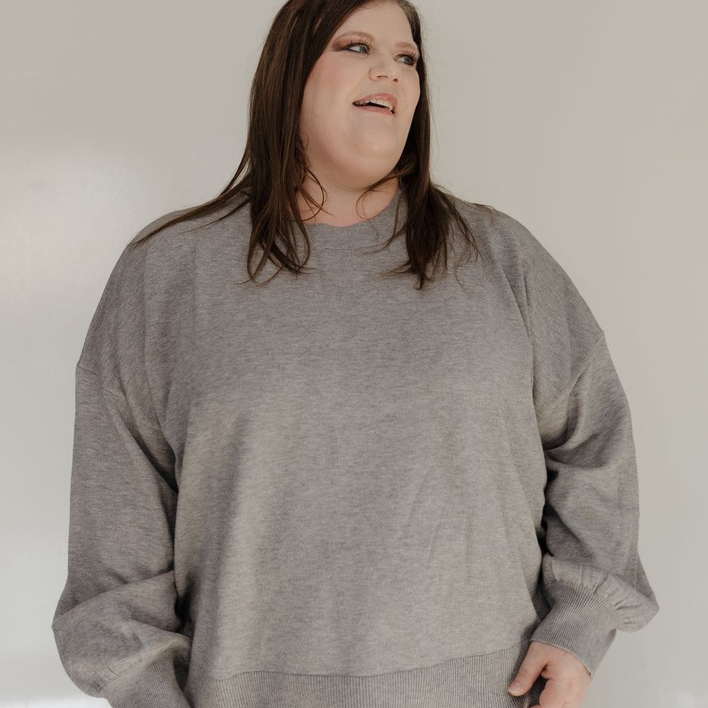 Person wearing a gray sweatshirt against a plain background